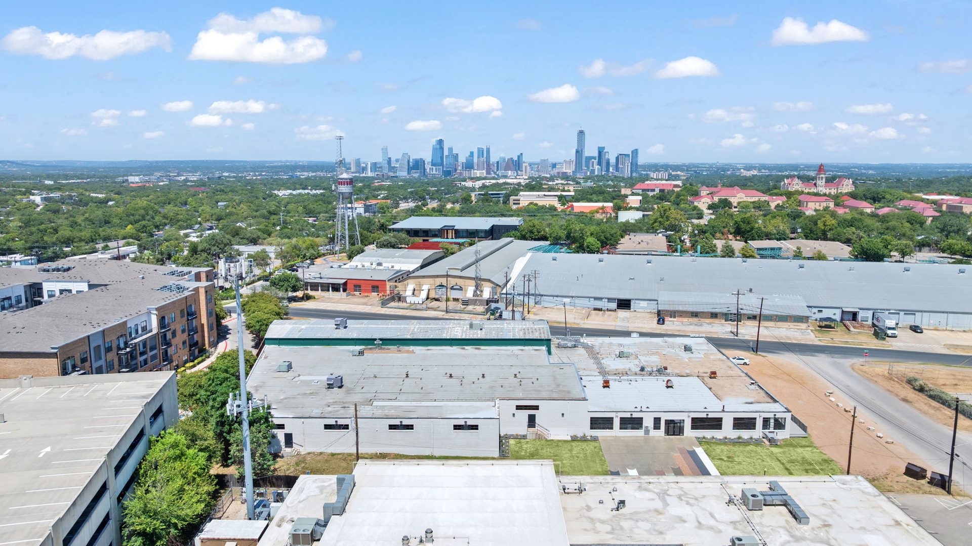 Aerial view of Austin with warehouses, apartments, and a distant downtown skyline.