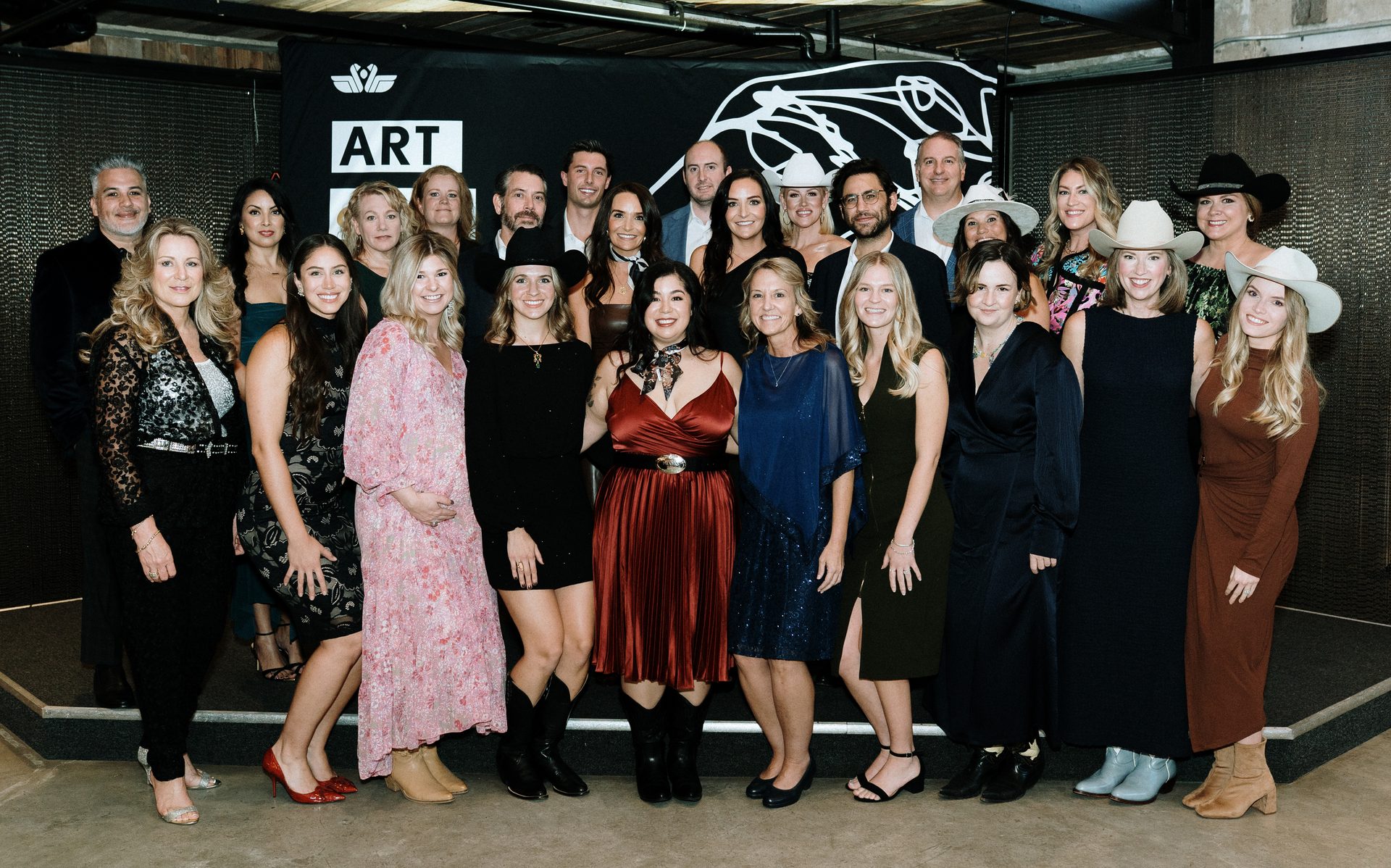 Large group of formally dressed adults posing for a photo in front of an ART logo.