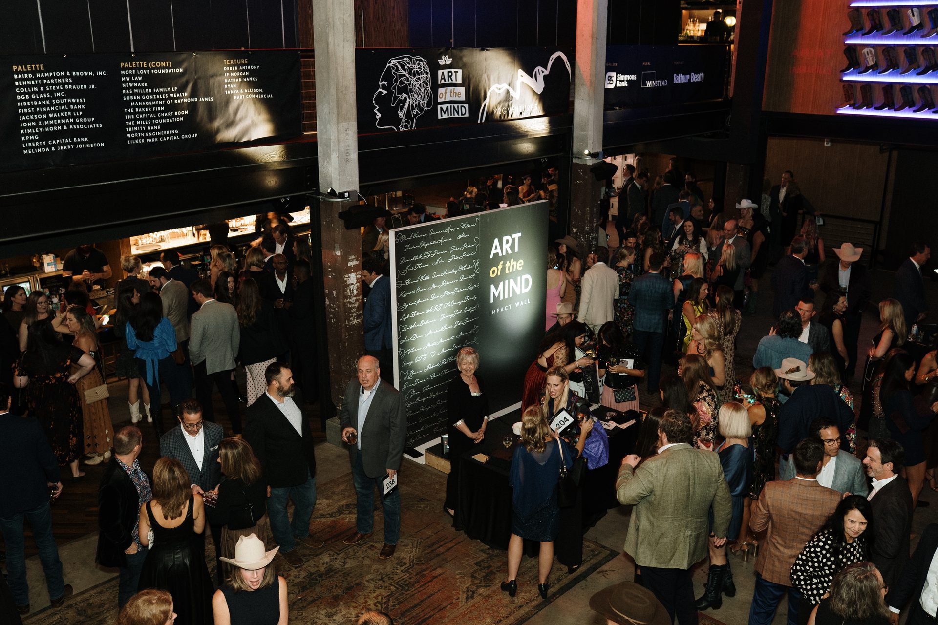 Overhead view of a crowded "Art of the Mind" event with guests mingling.