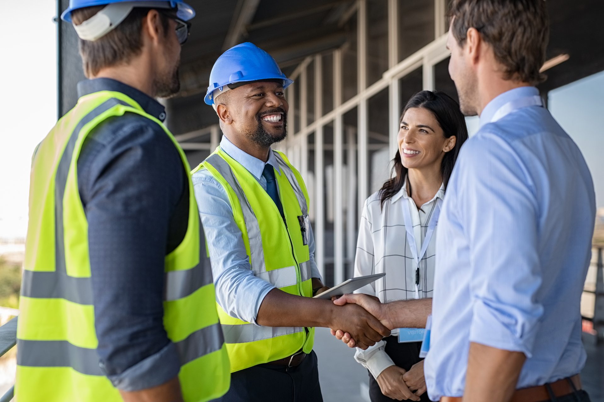 High-visibility clothing, Hard hat, Smile, Hand, Shirt, Workwear, Helmet, Sleeve, Handshake, Gesture