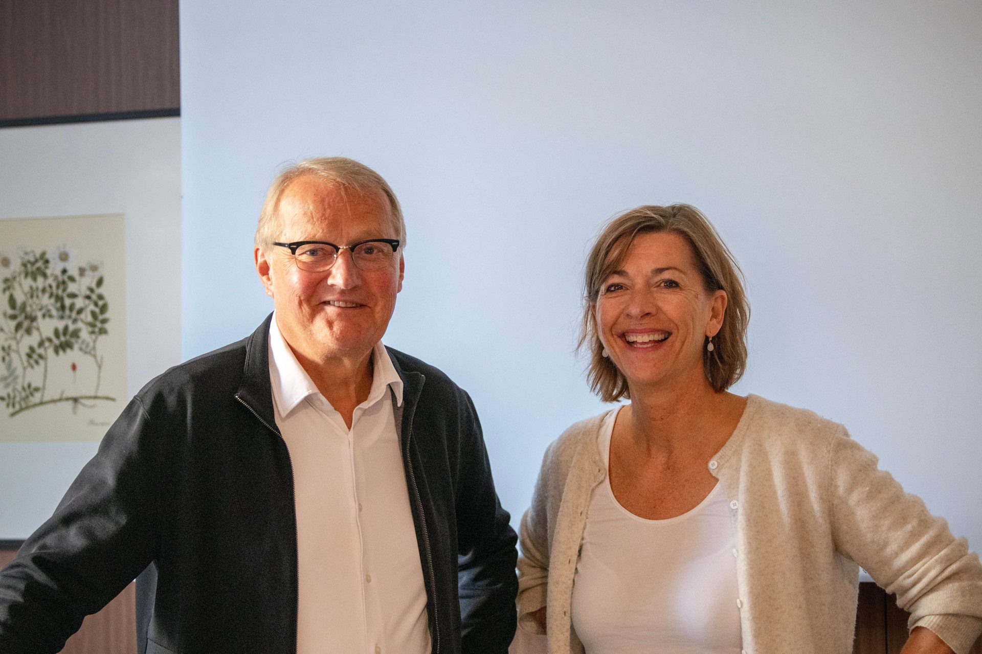 Smiling man with glasses and woman standing together.