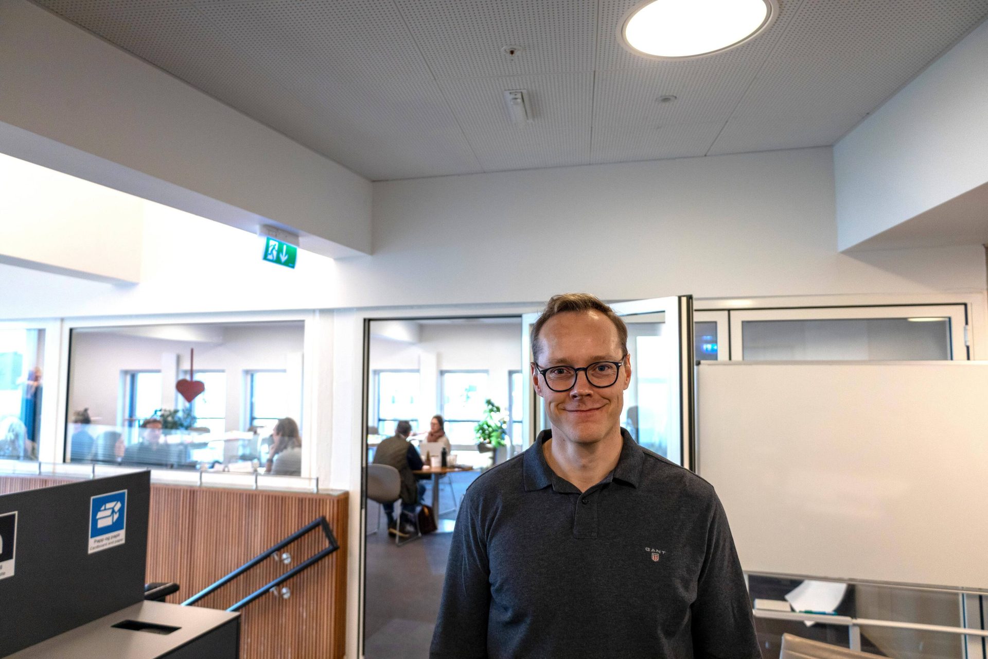 Smiling man with glasses in a modern office environment.