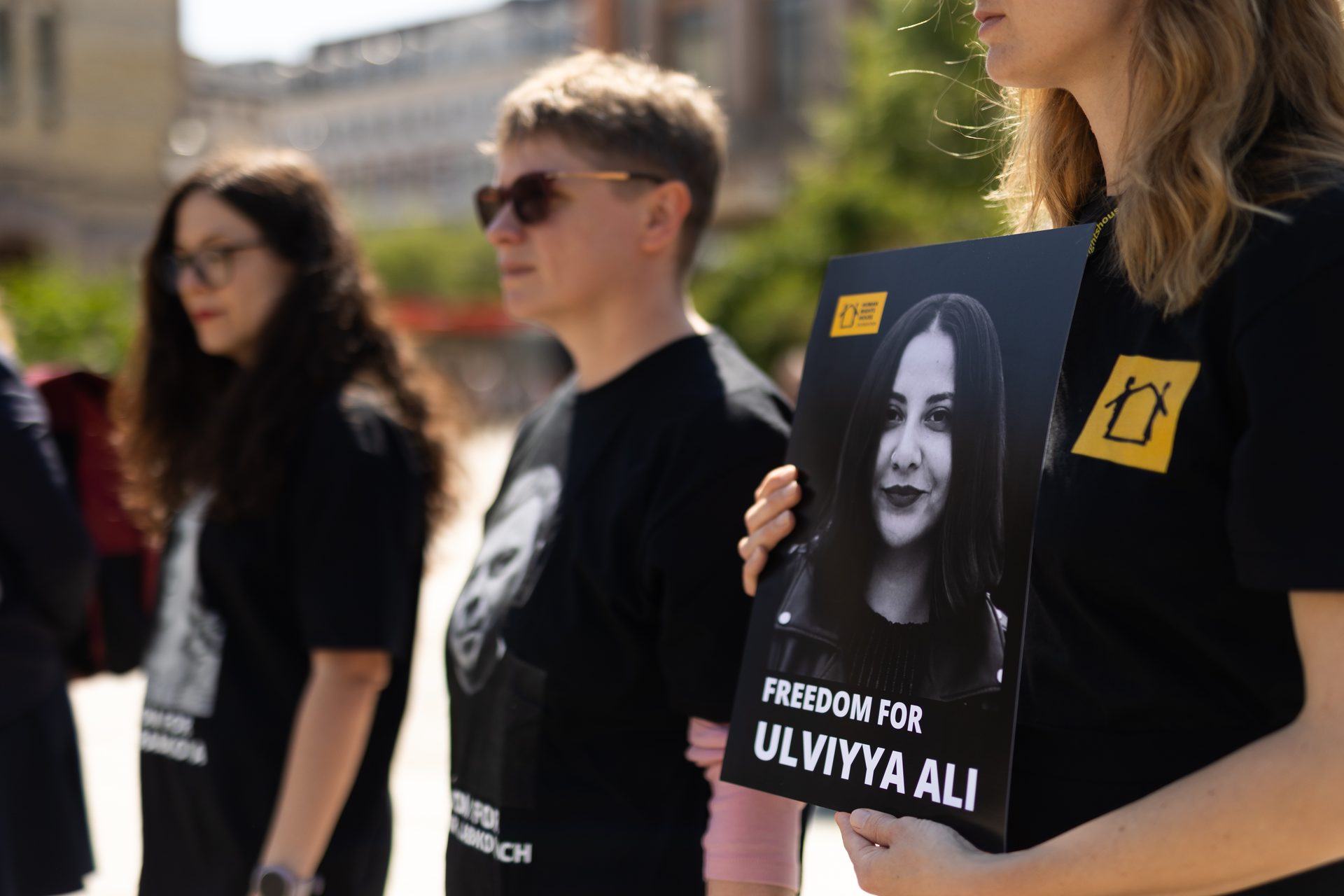 A person holds a sign with Ulviyya Ali's photo and 'Freedom for Ulviyya Ali' text at a protest.