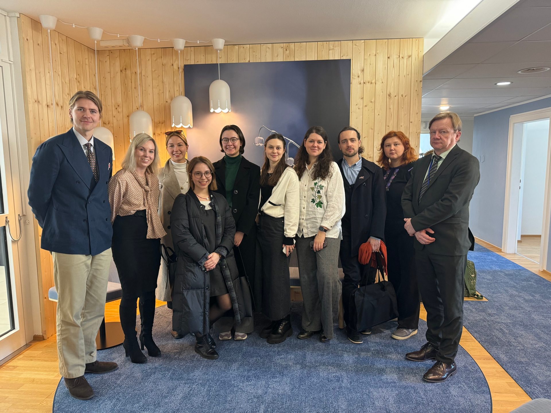 Interior design, Social group, Facial expression, White-collar worker, Smile, Trousers, Outerwear, Standing, Coat, Team