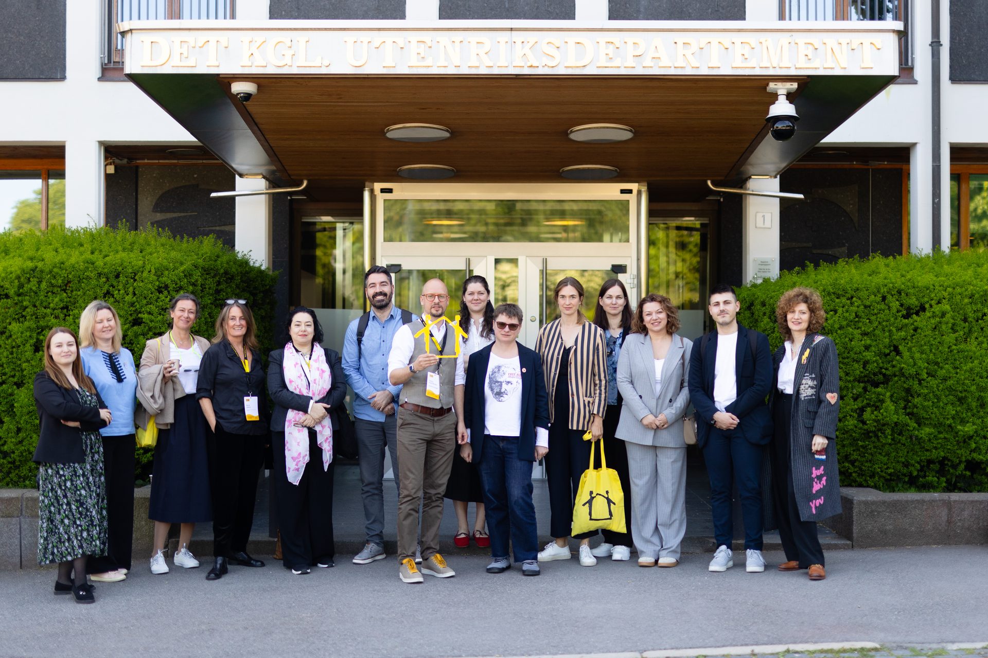 Group of people standing outside the Royal Ministry of Foreign Affairs building.