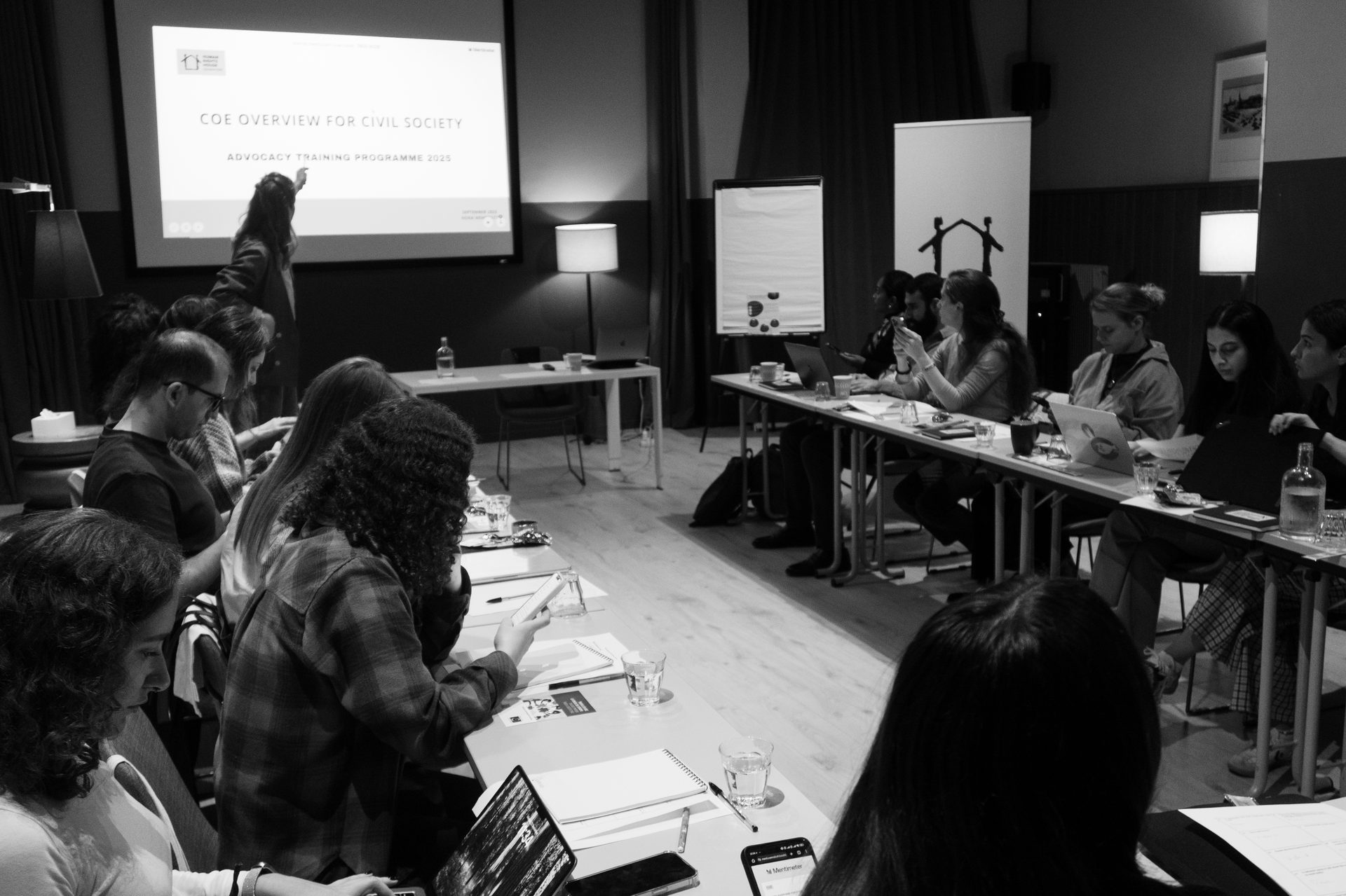 People attend an advocacy training workshop with a presenter and screen displaying 'COE Overview for Civil Society'.