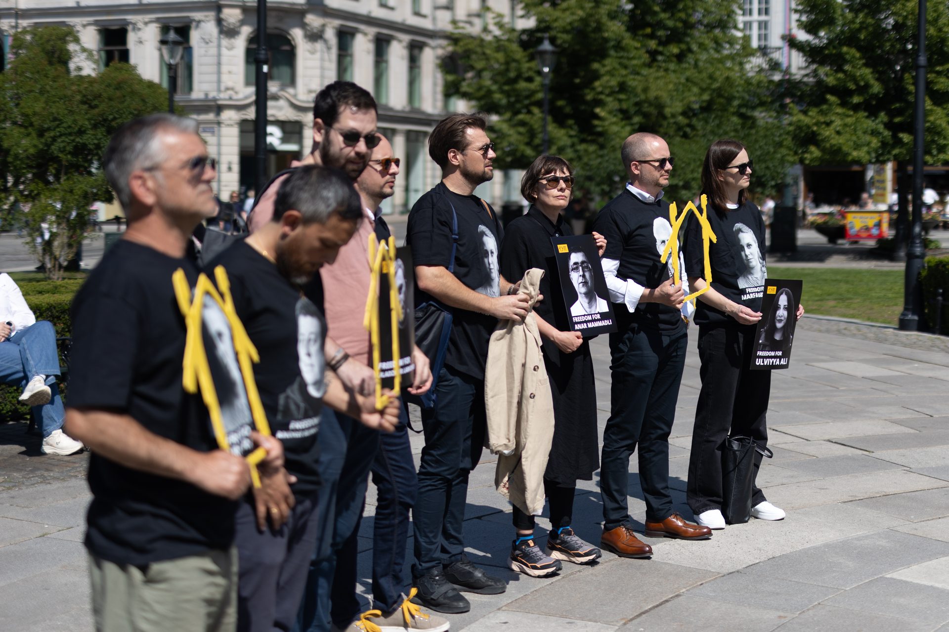 A group holds signs with photos of Anar Mammamli and Ulviyya Ali, demanding their freedom.