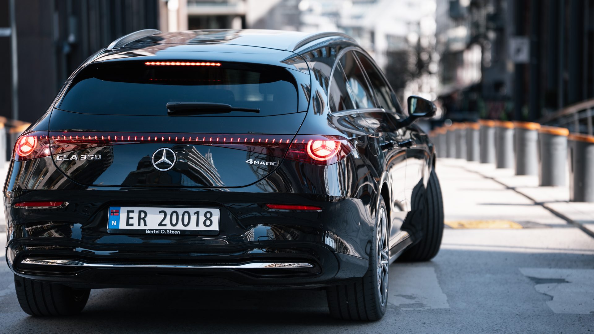 A black Mercedes-Benz EQA 350 SUV parked on a city street, viewed from the rear-left, showcasing its taillights.
