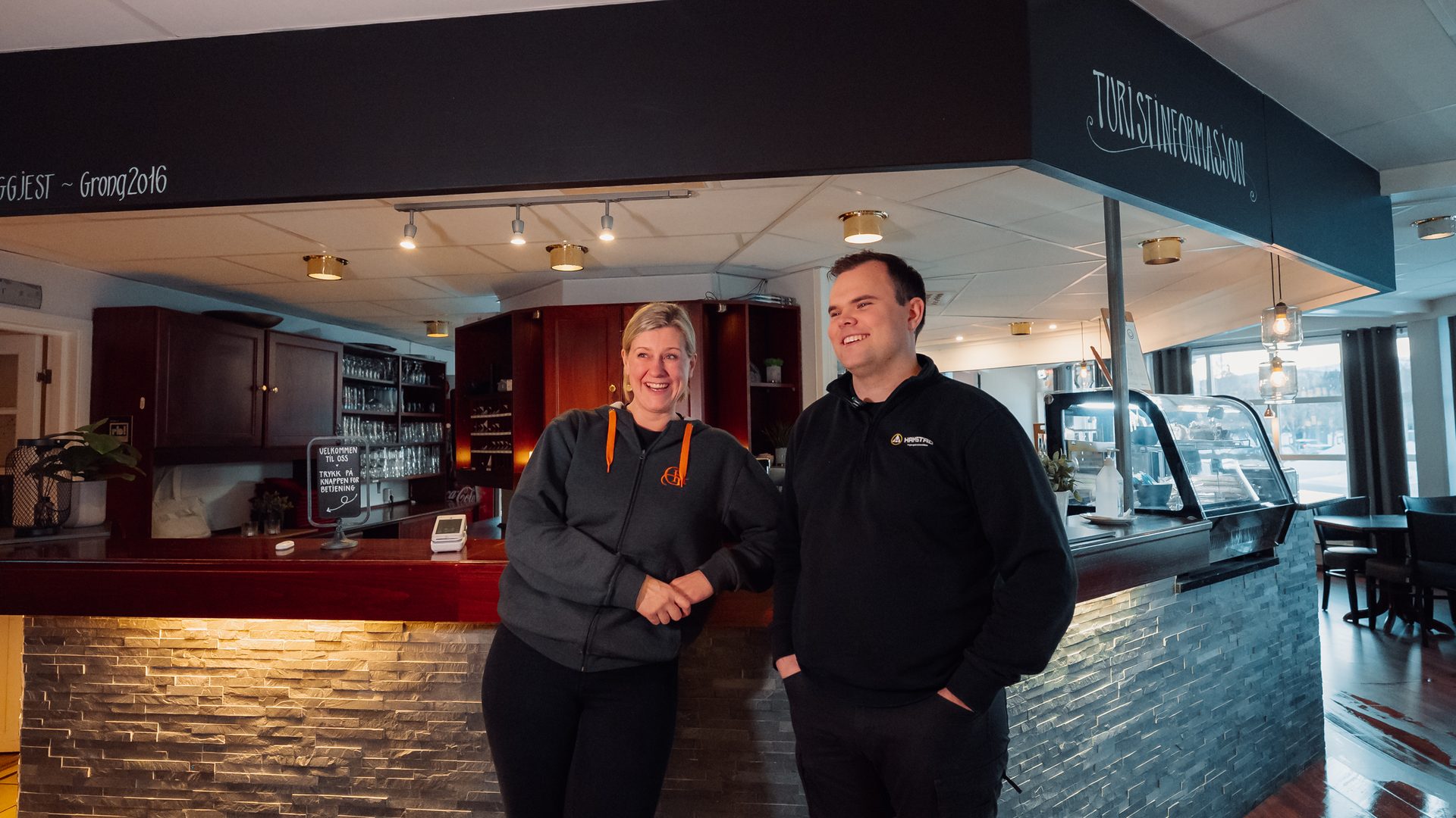 Two happy staff members behind a tourist information counter.