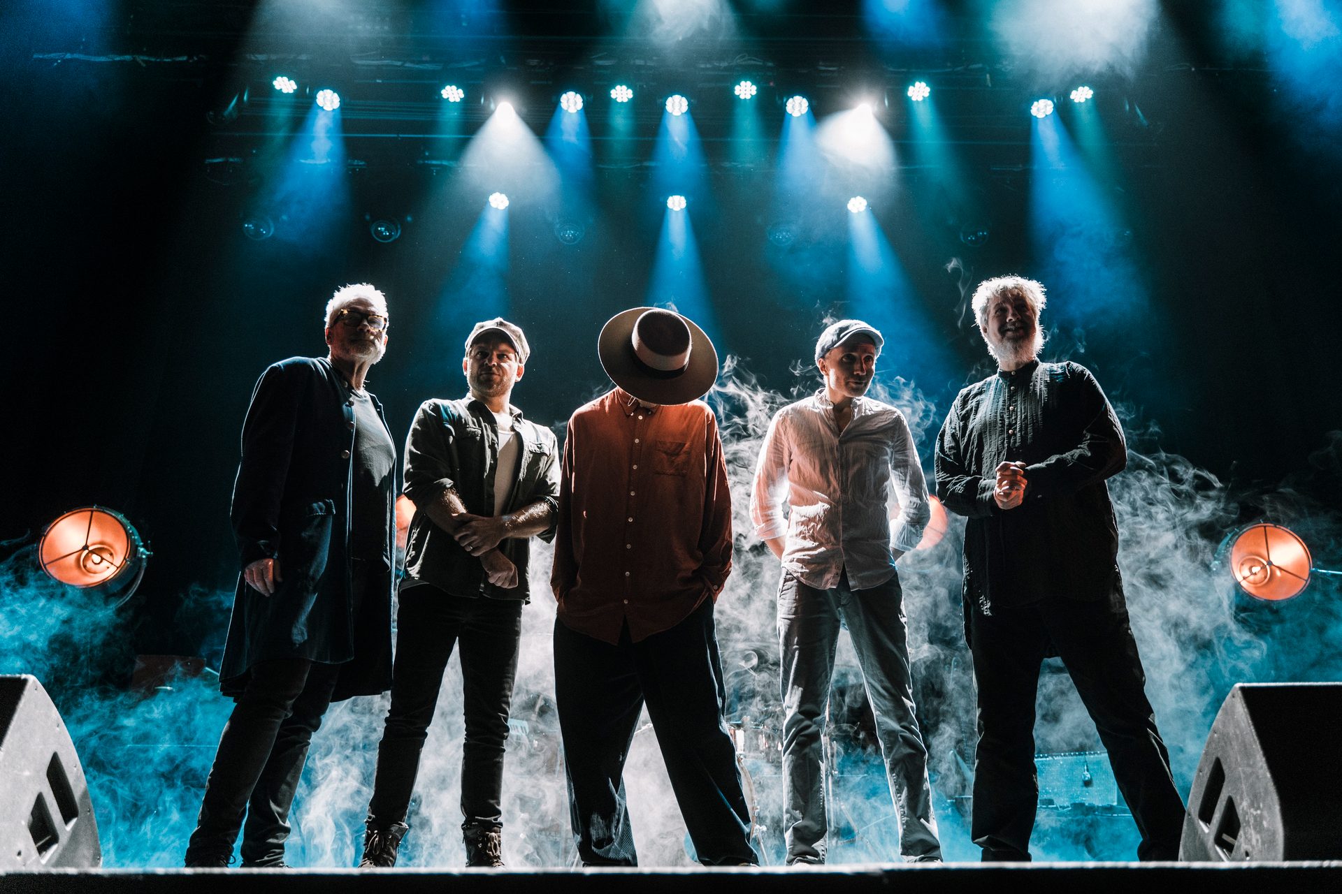 Five men on a smoky stage under blue spotlights.