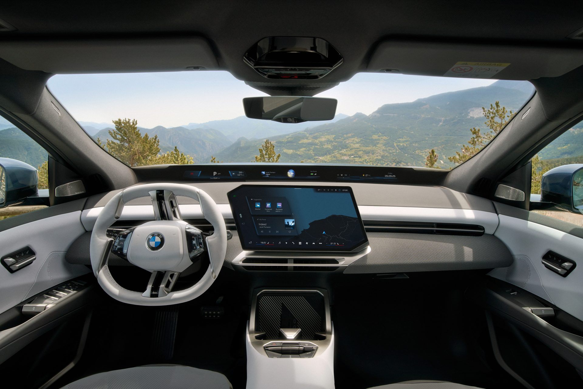 Modern BMW car interior with a large display screen and a mountain view.