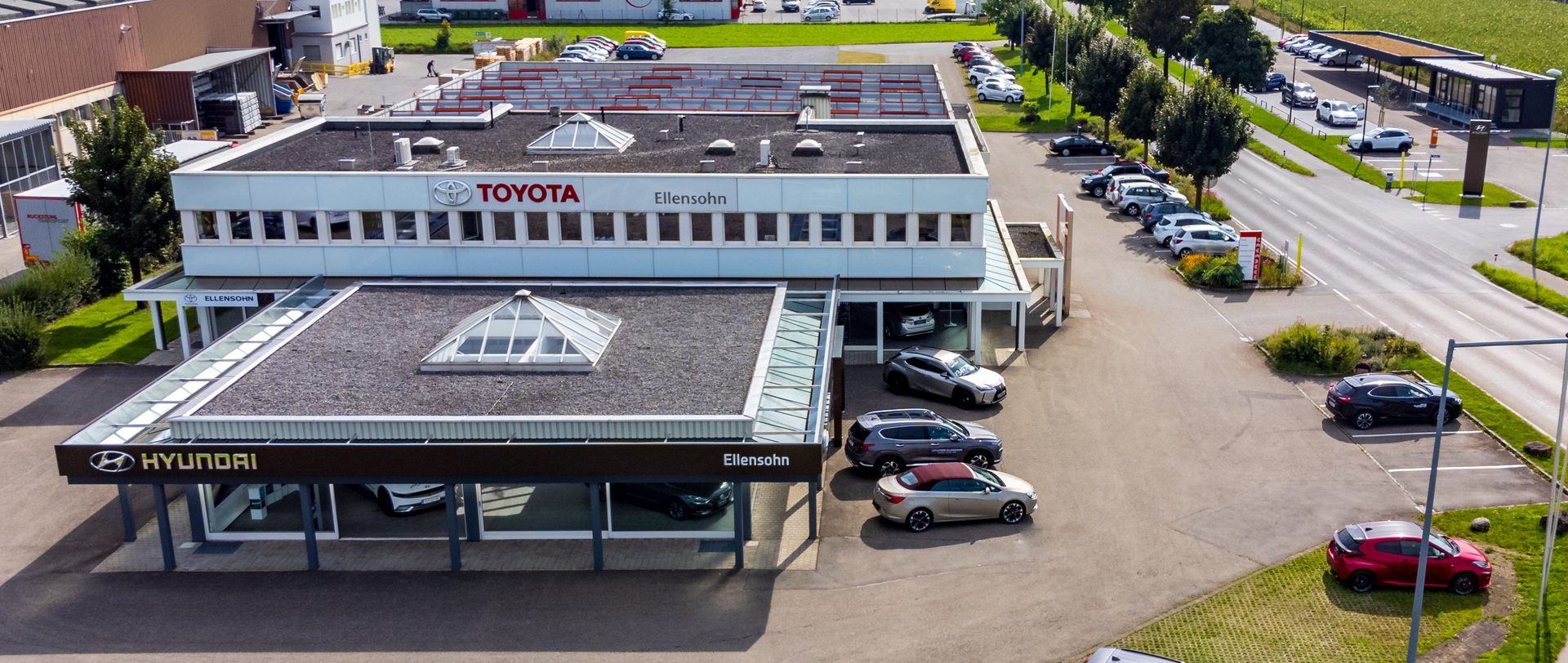 Aerial shot of the Ellensohn car dealership, featuring separate Toyota and Hyundai buildings with many cars parked.
