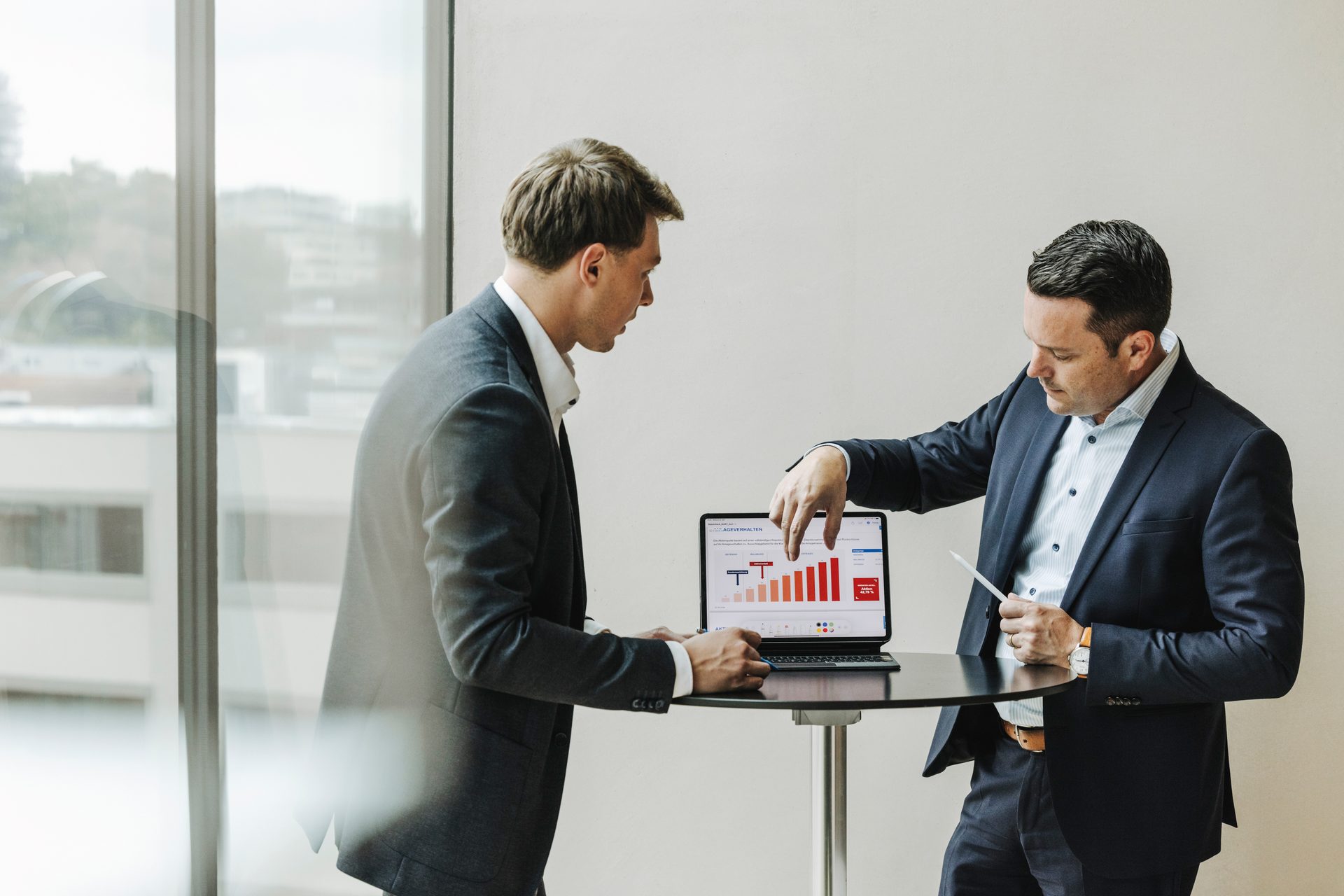 Two businessmen discussing data on a laptop screen.