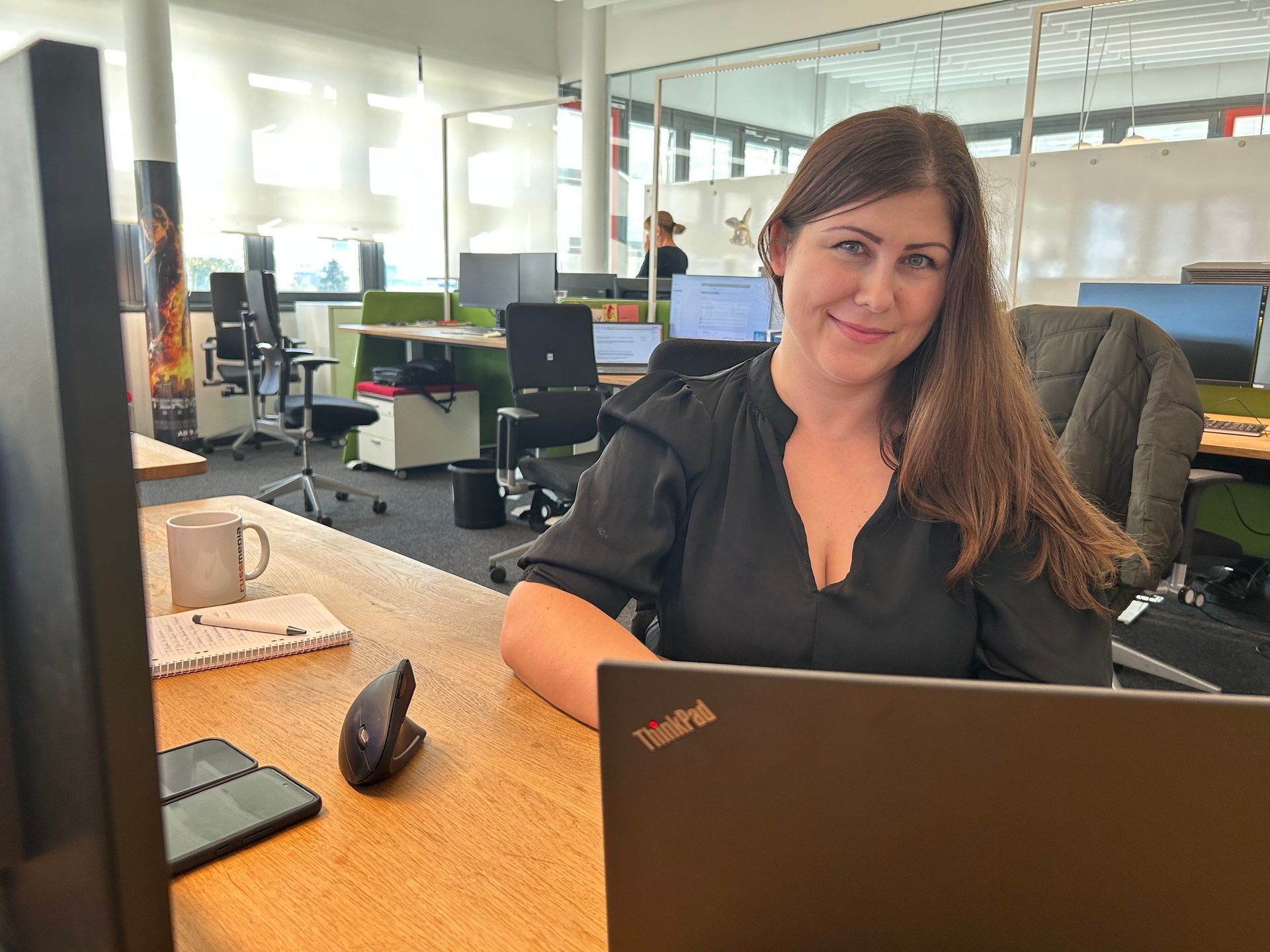 Smiling woman at an office desk with a laptop.