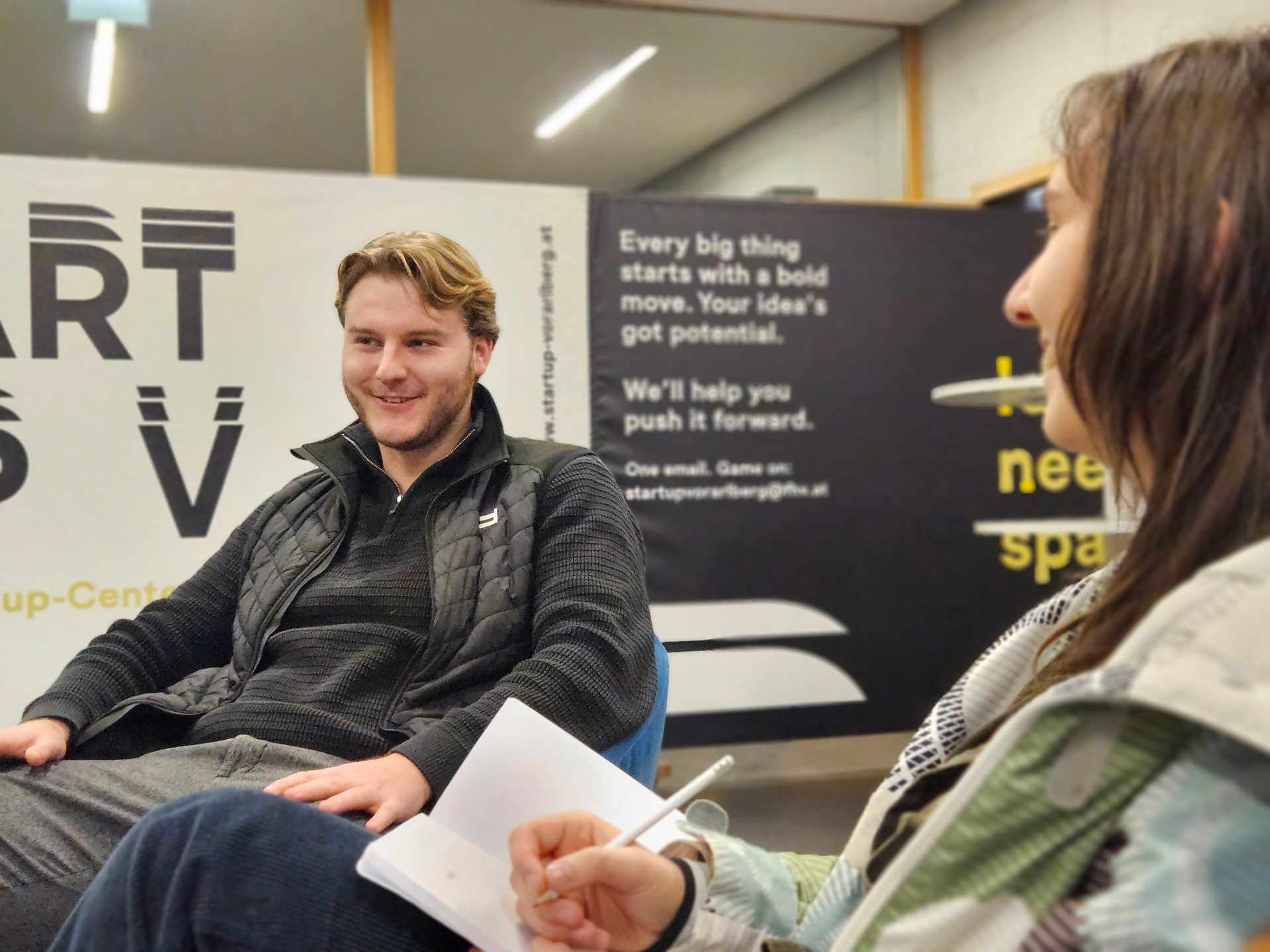 Man smiles at woman taking notes during a startup discussion.