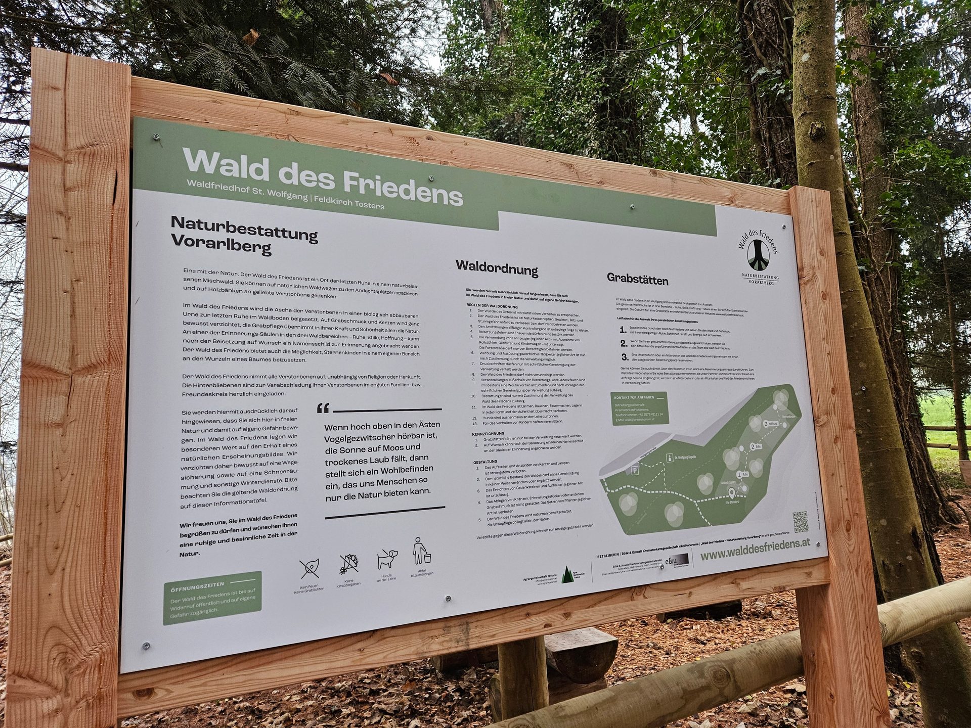 A wooden sign about "Wald des Friedens" (Forest of Peace) natural burial ground in a forest.