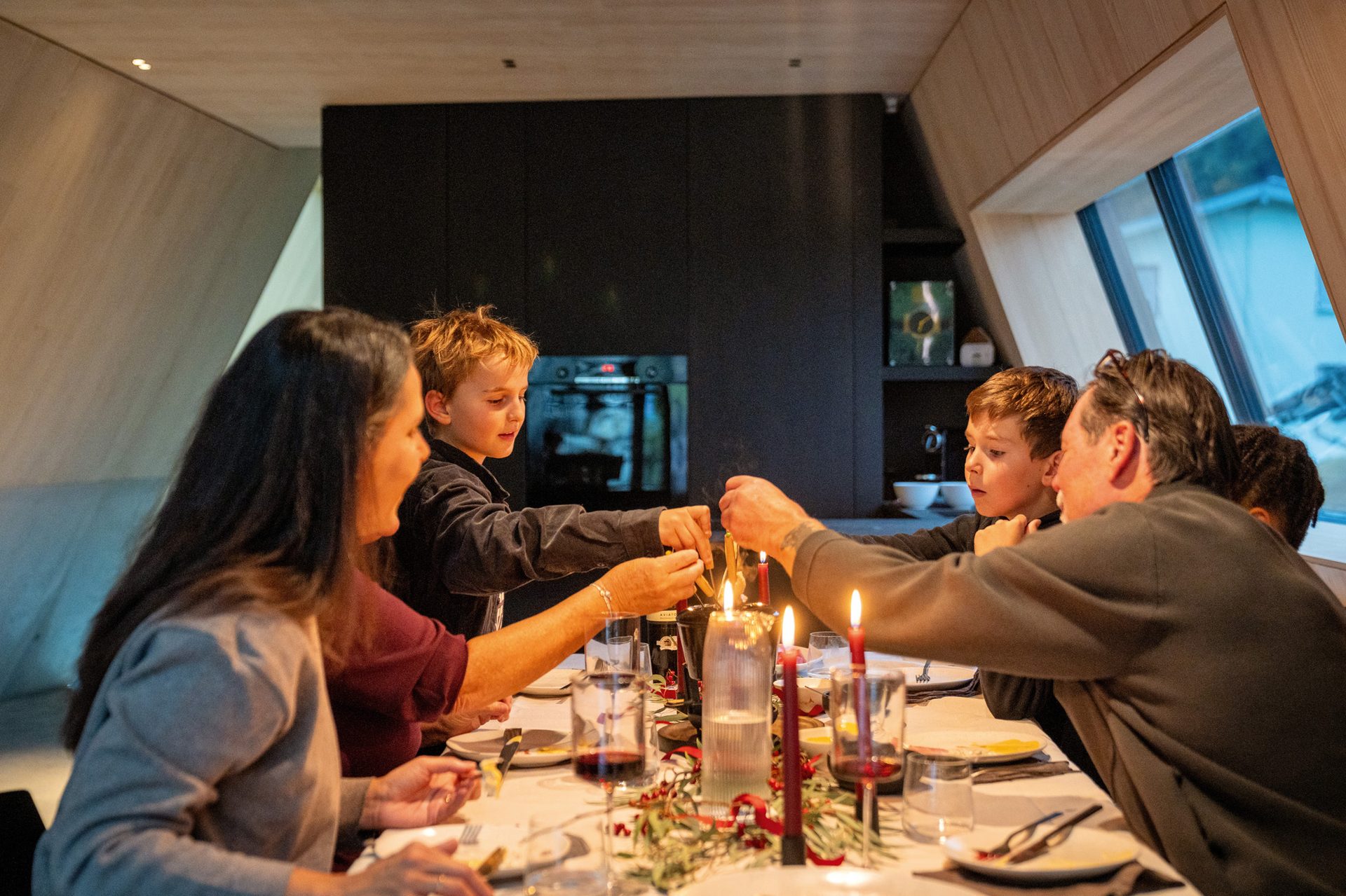Family lighting candles together at a dining table.