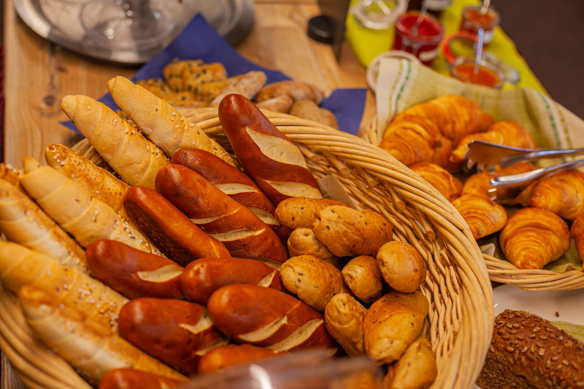 A breakfast buffet table with two baskets, one filled with various bread rolls and the other with croissants.
