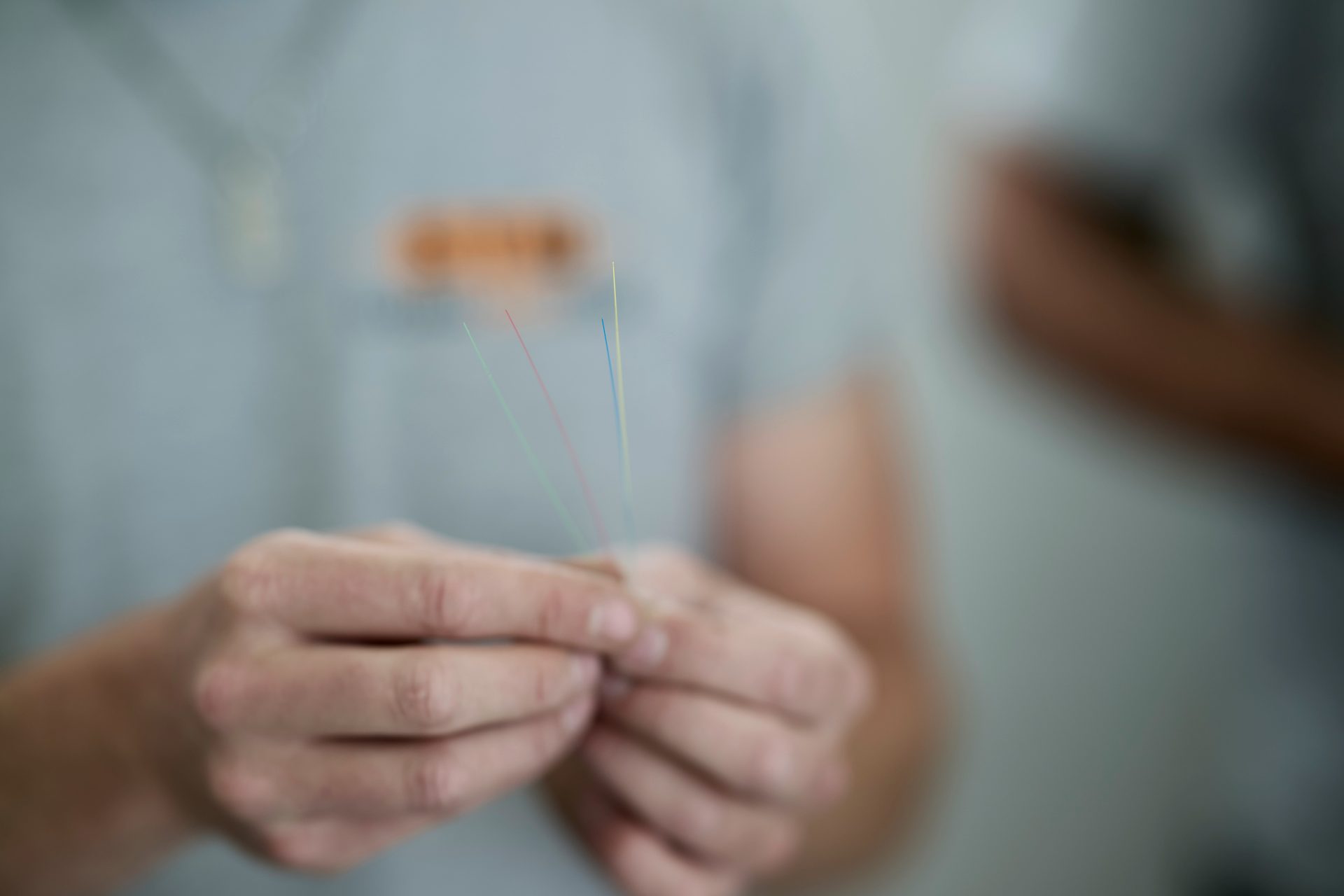 Close-up of hands holding colorful fiber optic strands, highlighting connectivity and technology.