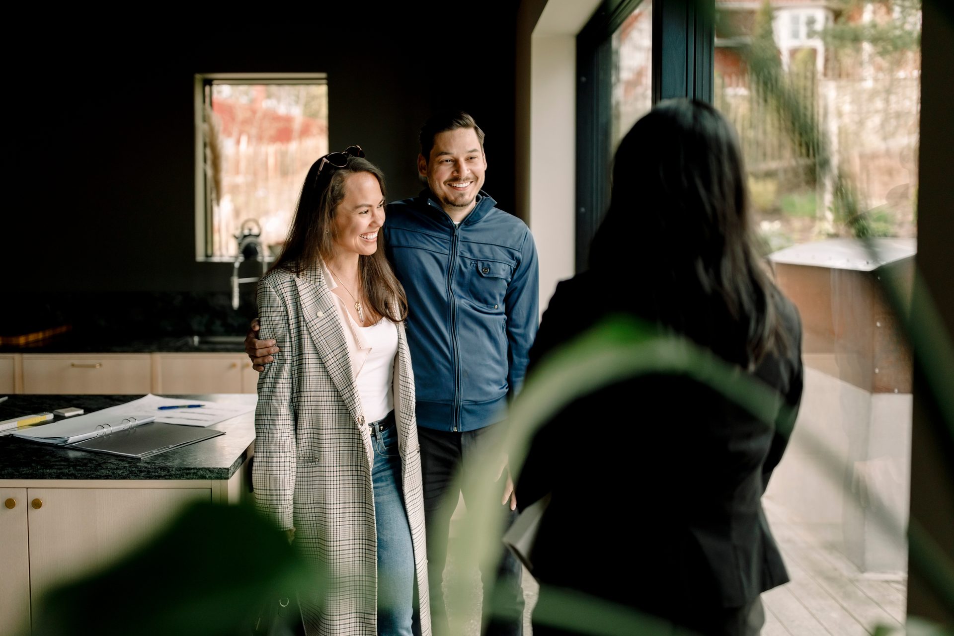 A smiling couple interacts with an agent in a modern home.