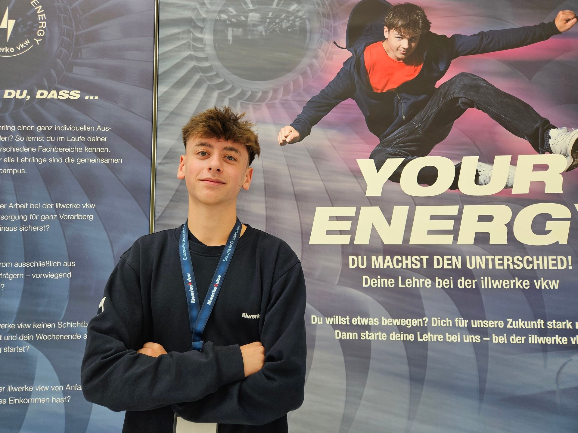 Young man in front of illwerke vkw energy company apprenticeship banner.