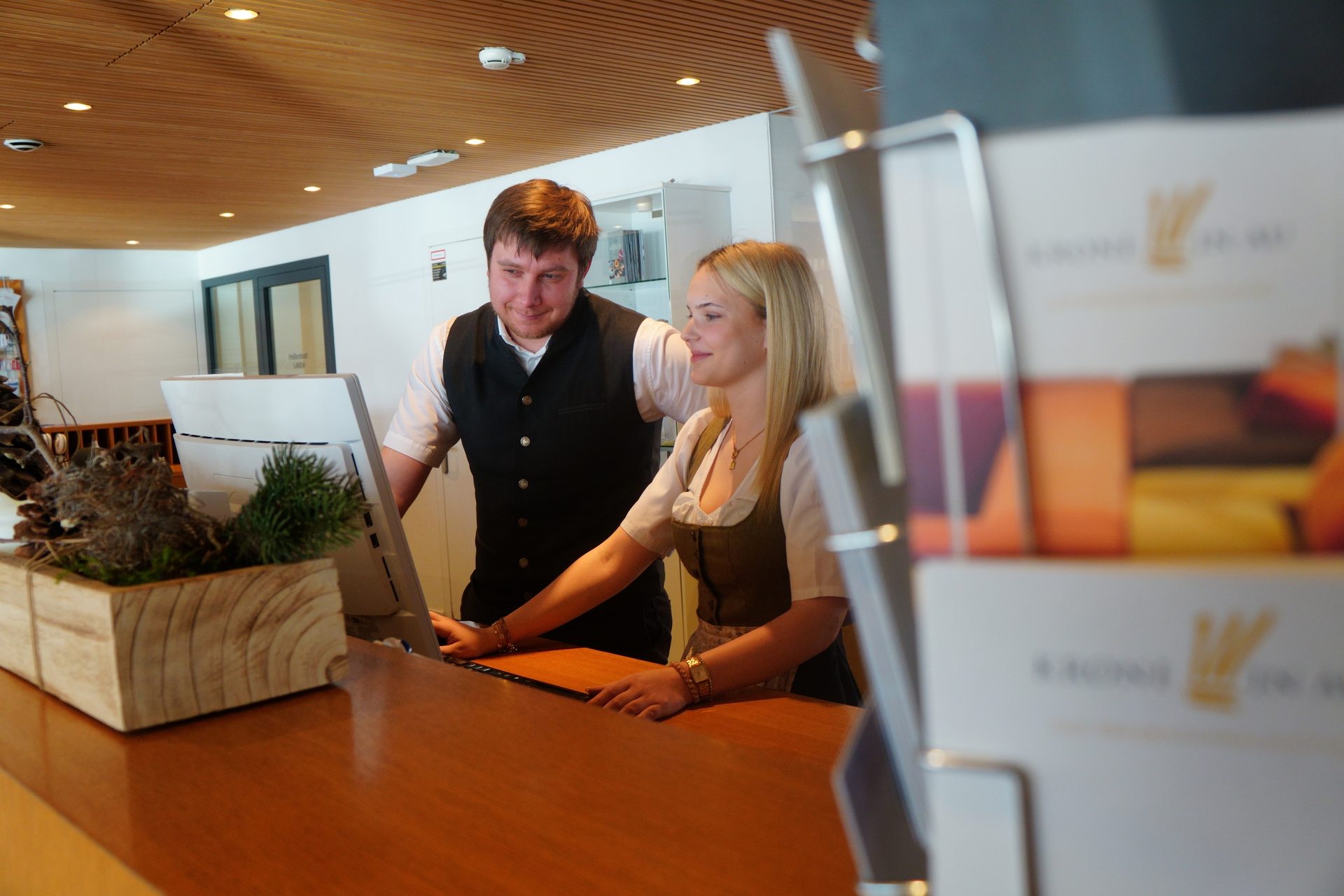 Man and woman in traditional attire at hotel reception desk with computer.
