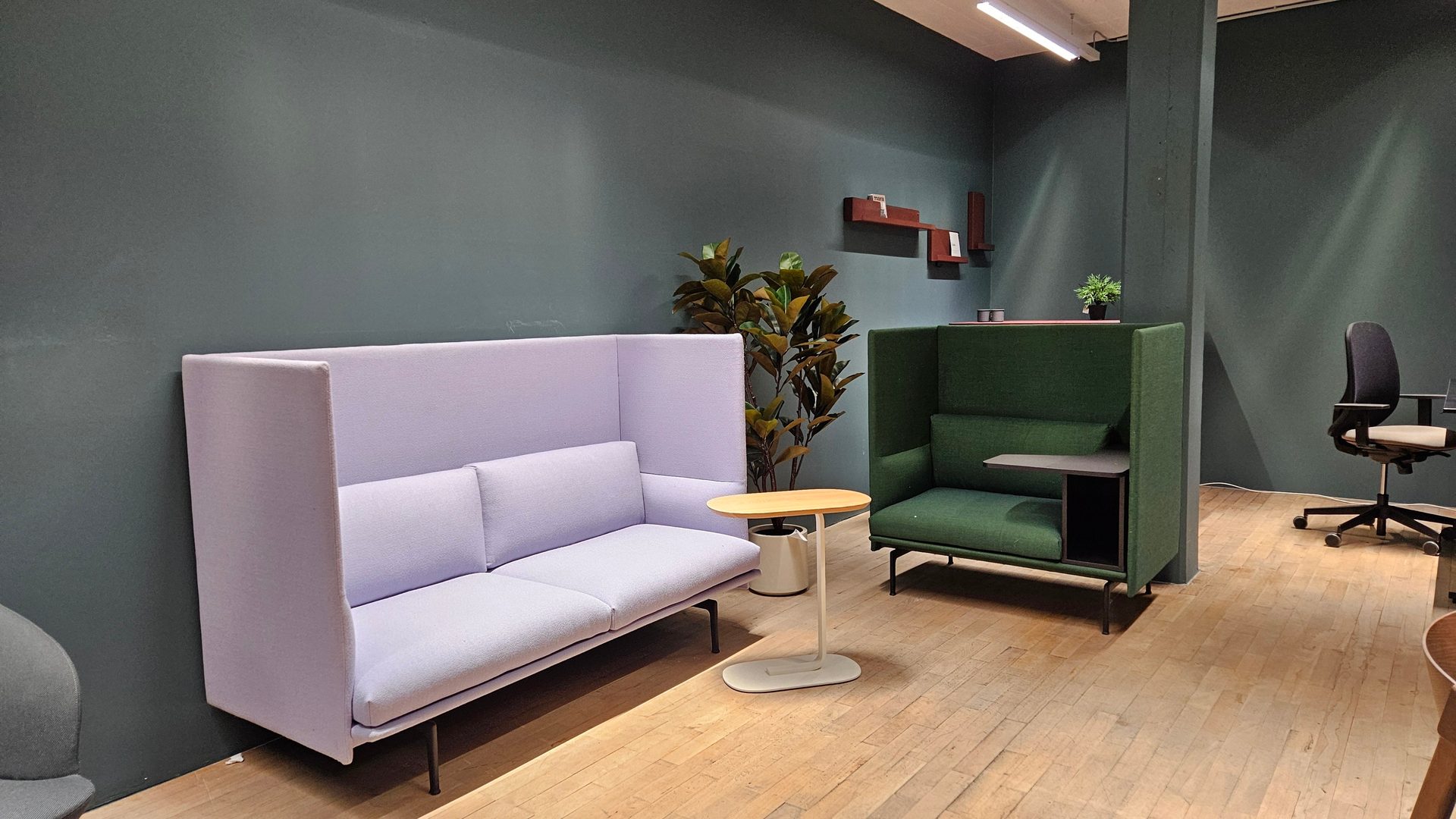 A contemporary office features high-back purple sofa and green armchair for privacy.