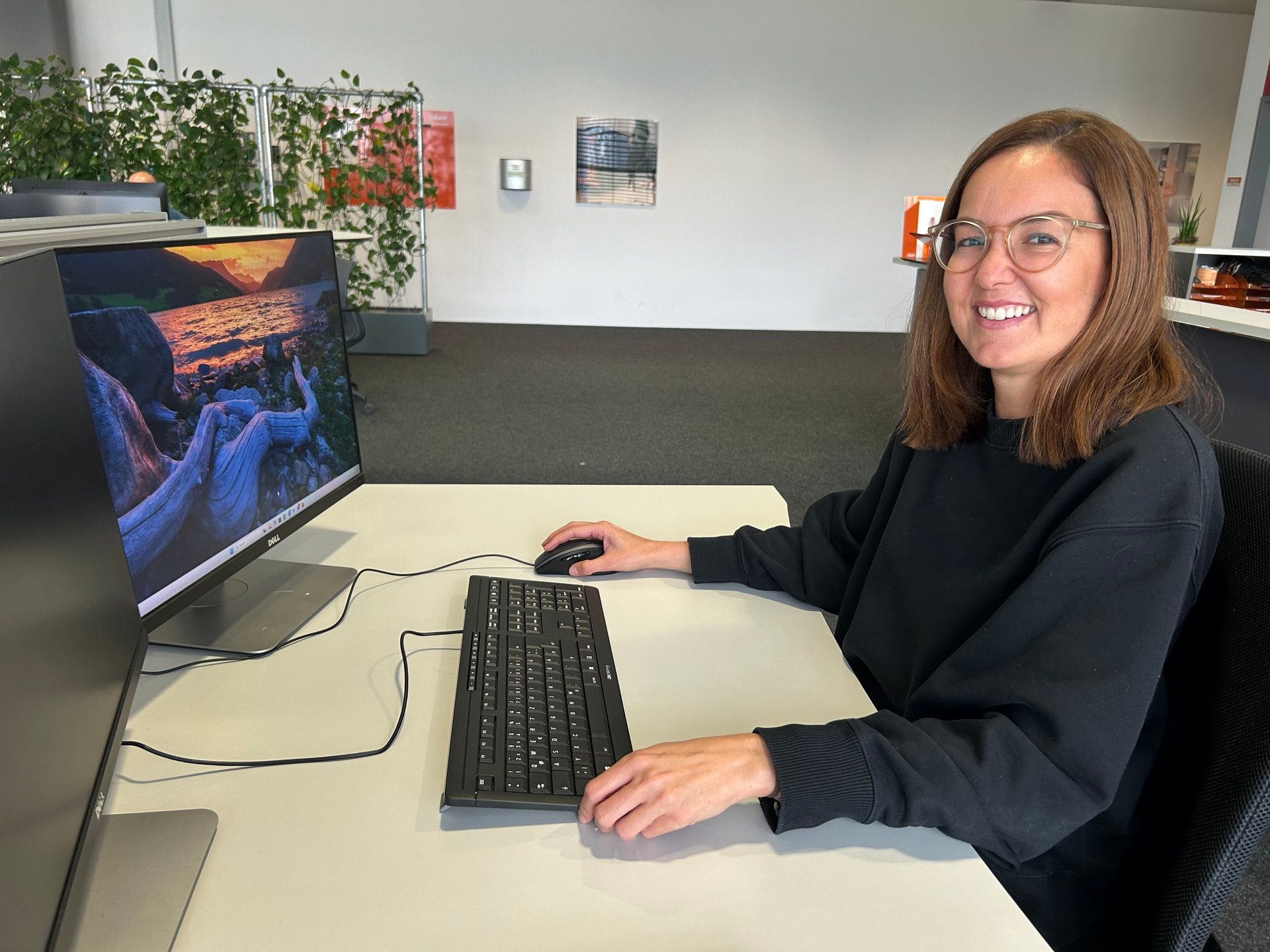 Smiling woman at desk with computer.