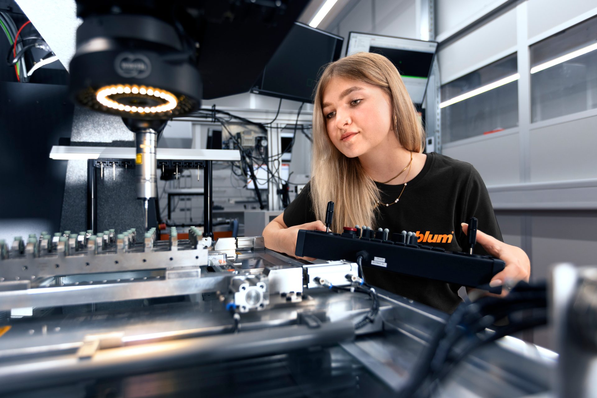Woman operating industrial machine with a ring light and control panel.