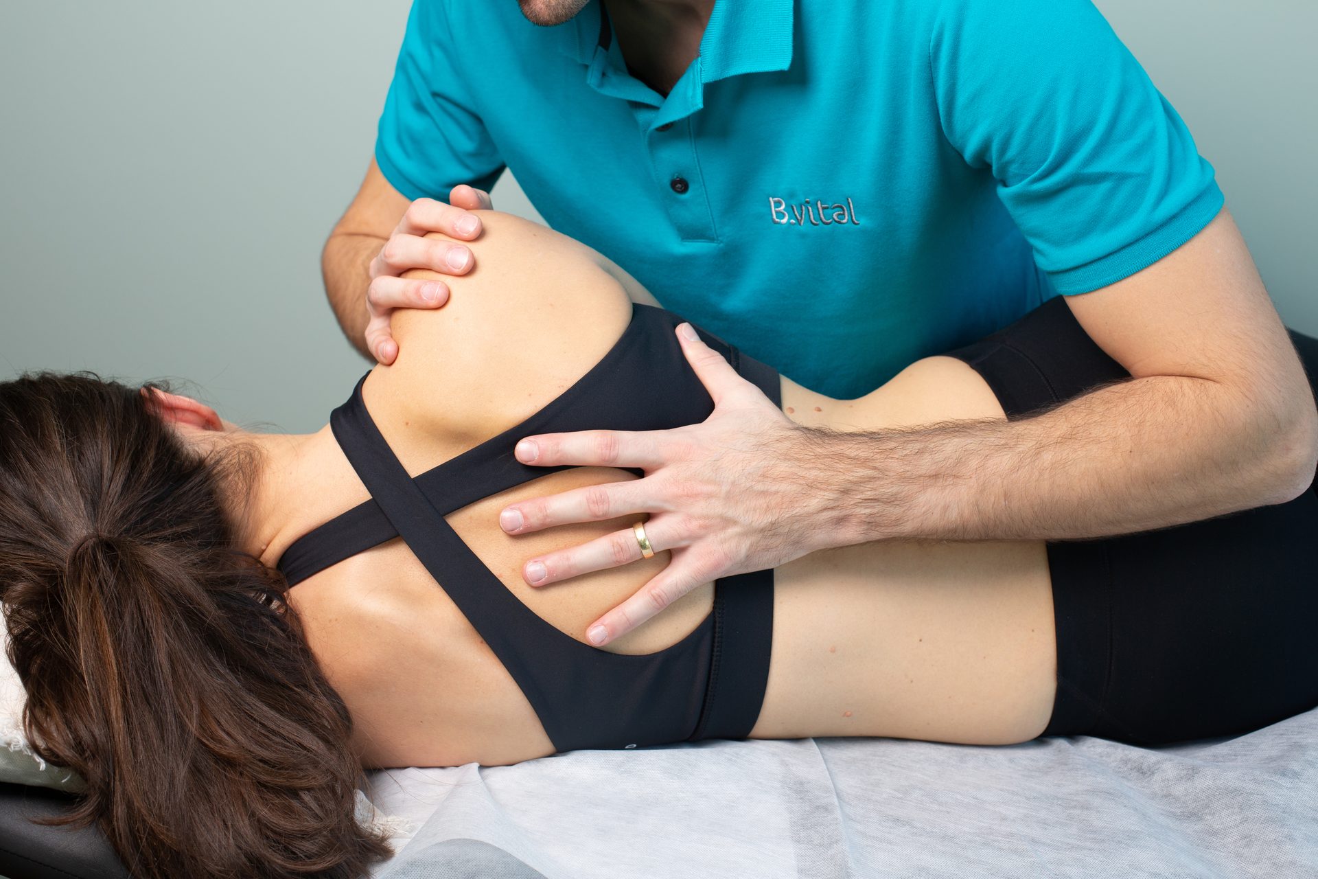 Chiropractor adjusting a female patient's upper back on a treatment table.