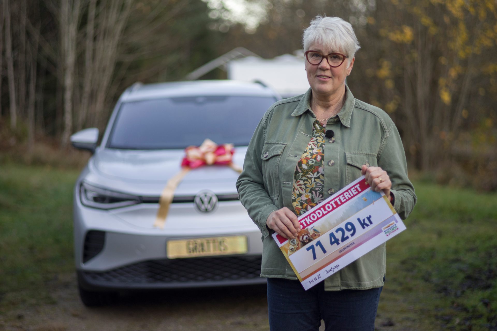 Woman with lottery winnings (71,429 kr) and new car with a bow.