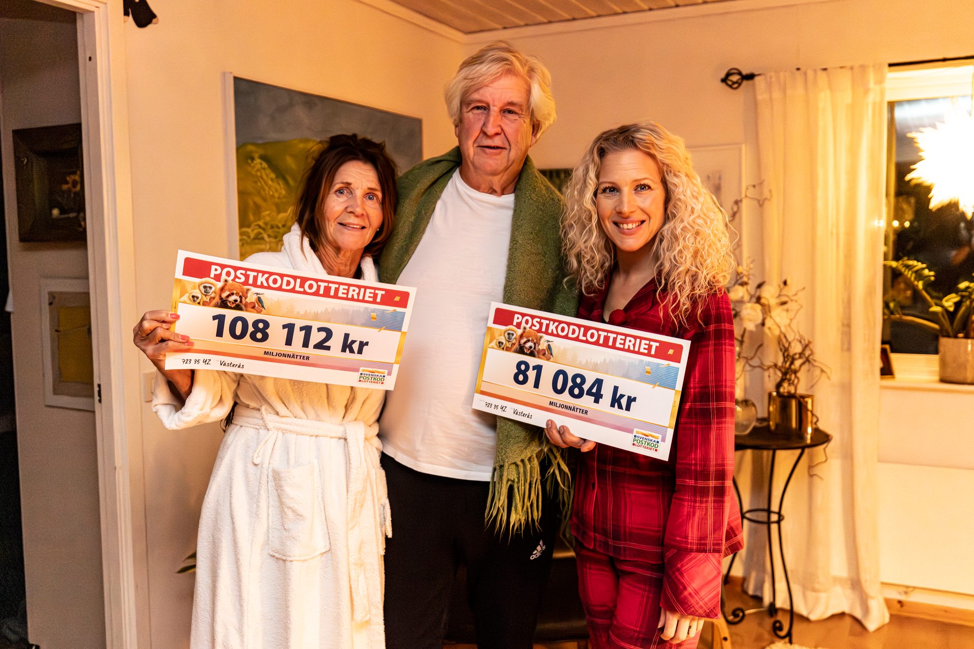 Three people smiling and holding lottery signs showing winnings of 108,112 kr and 81,084 kr.