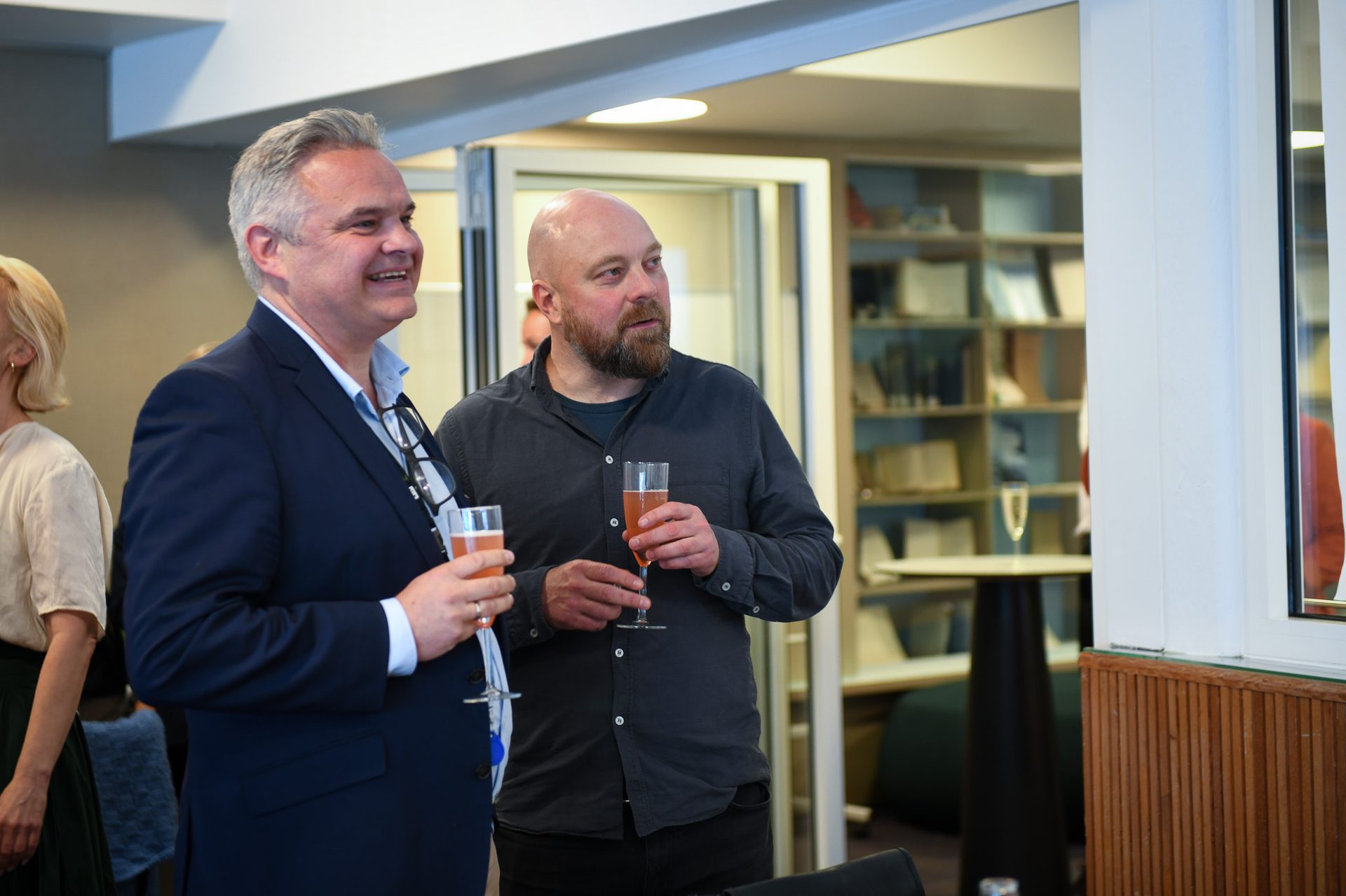 Two men holding sparkling wine, one smiling.