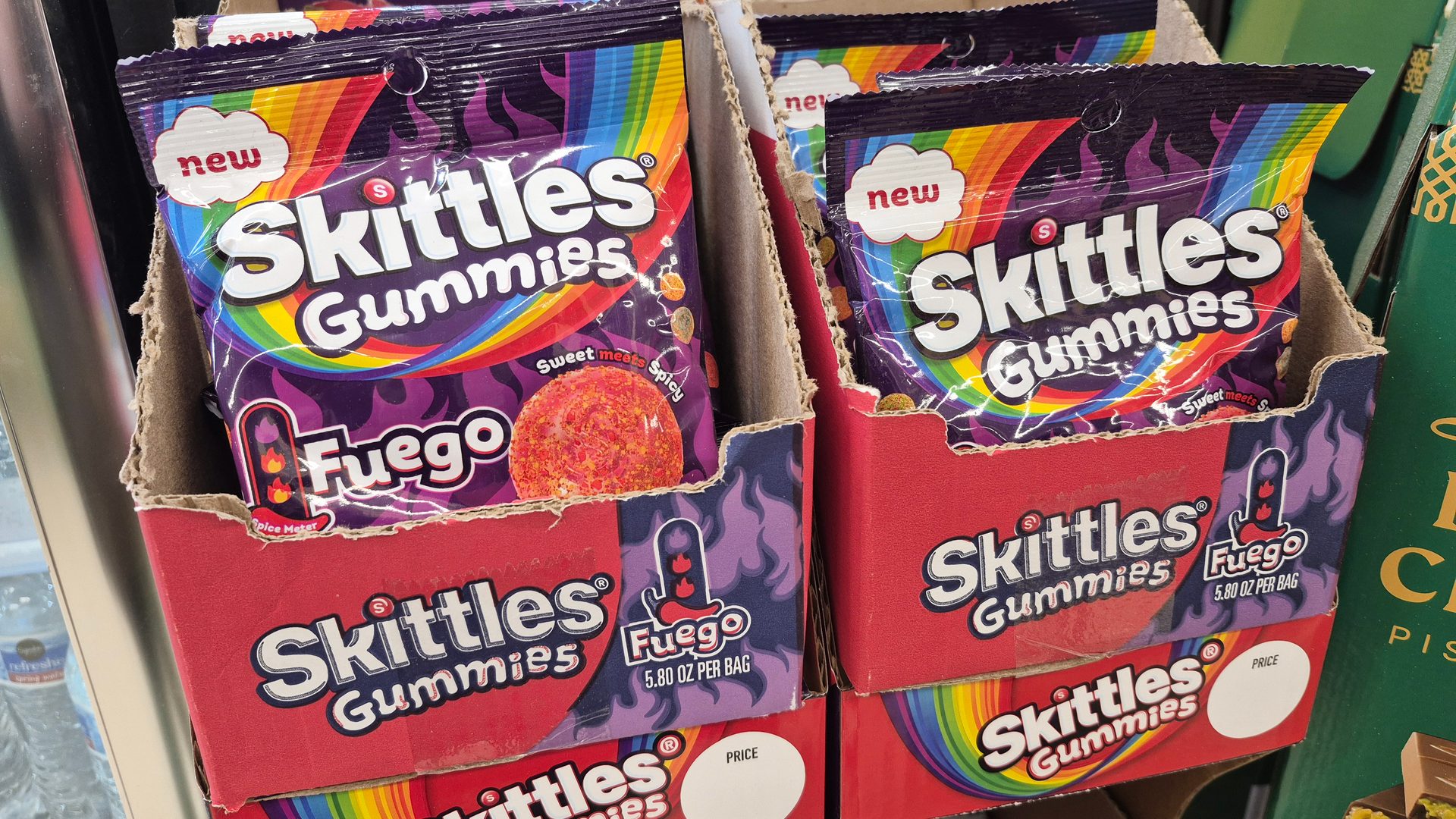 New Skittles Gummies Fuego candy bags, labeled "Sweet meets Spicy," displayed in a store.
