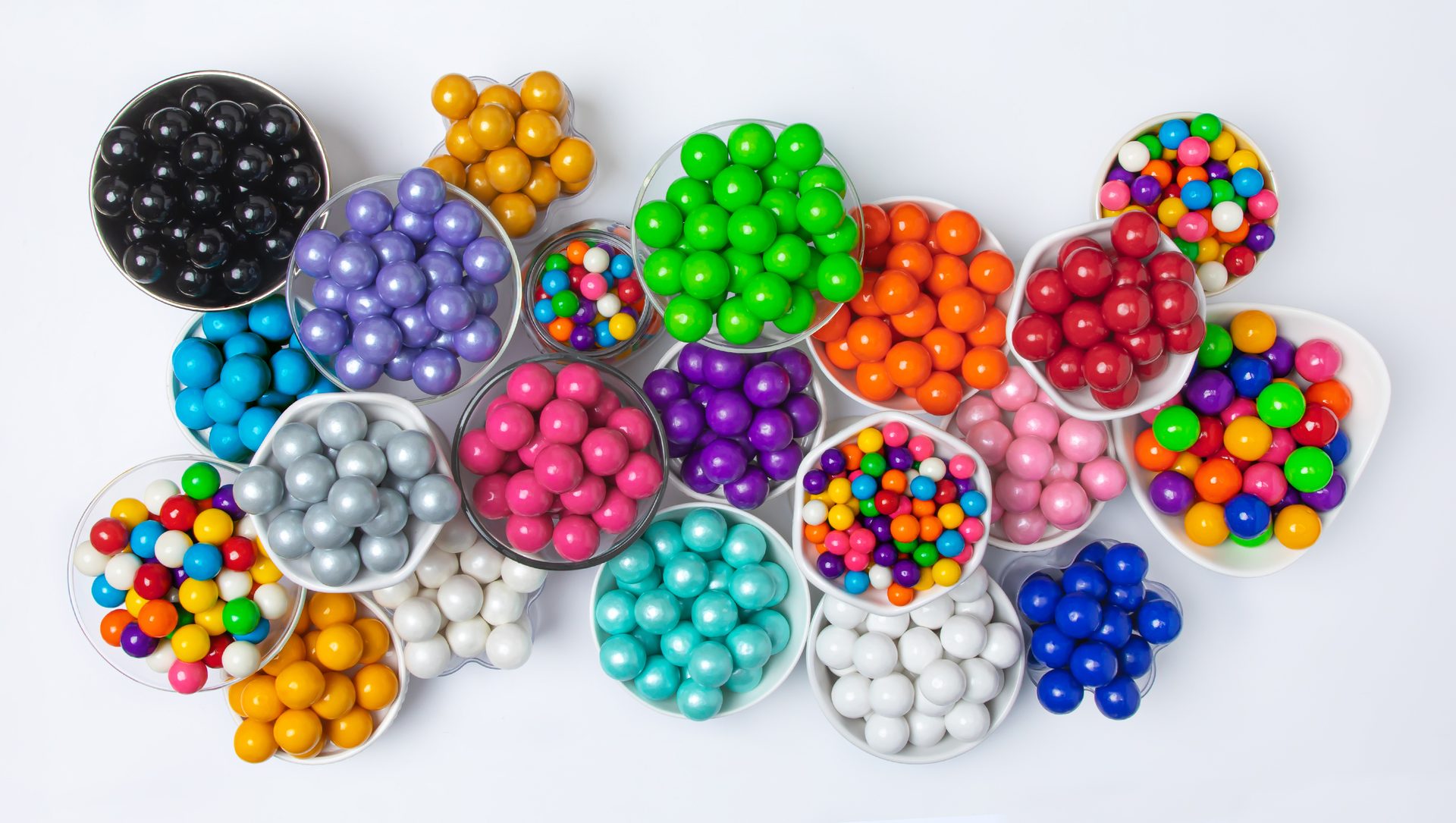 Bowls of colored gumballs arranged on a white background