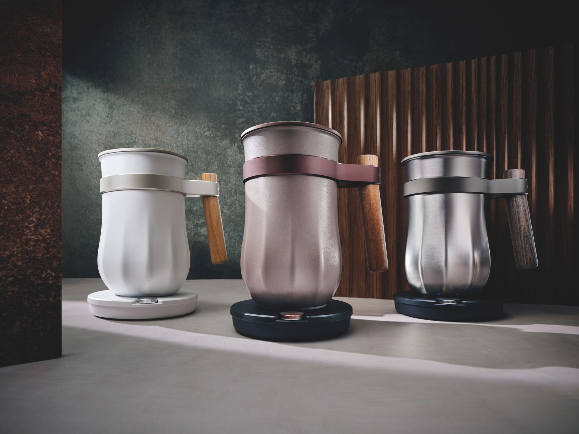 Three sleek electric kettles: white, rose gold, and silver, with wooden handles.