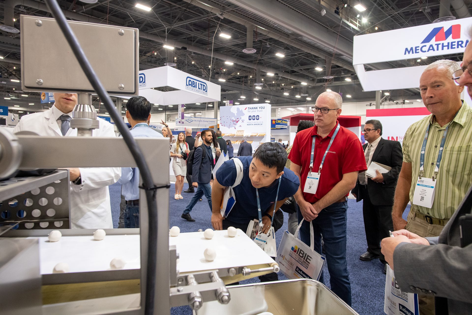 Group of men examining dough balls on conveyor belt
