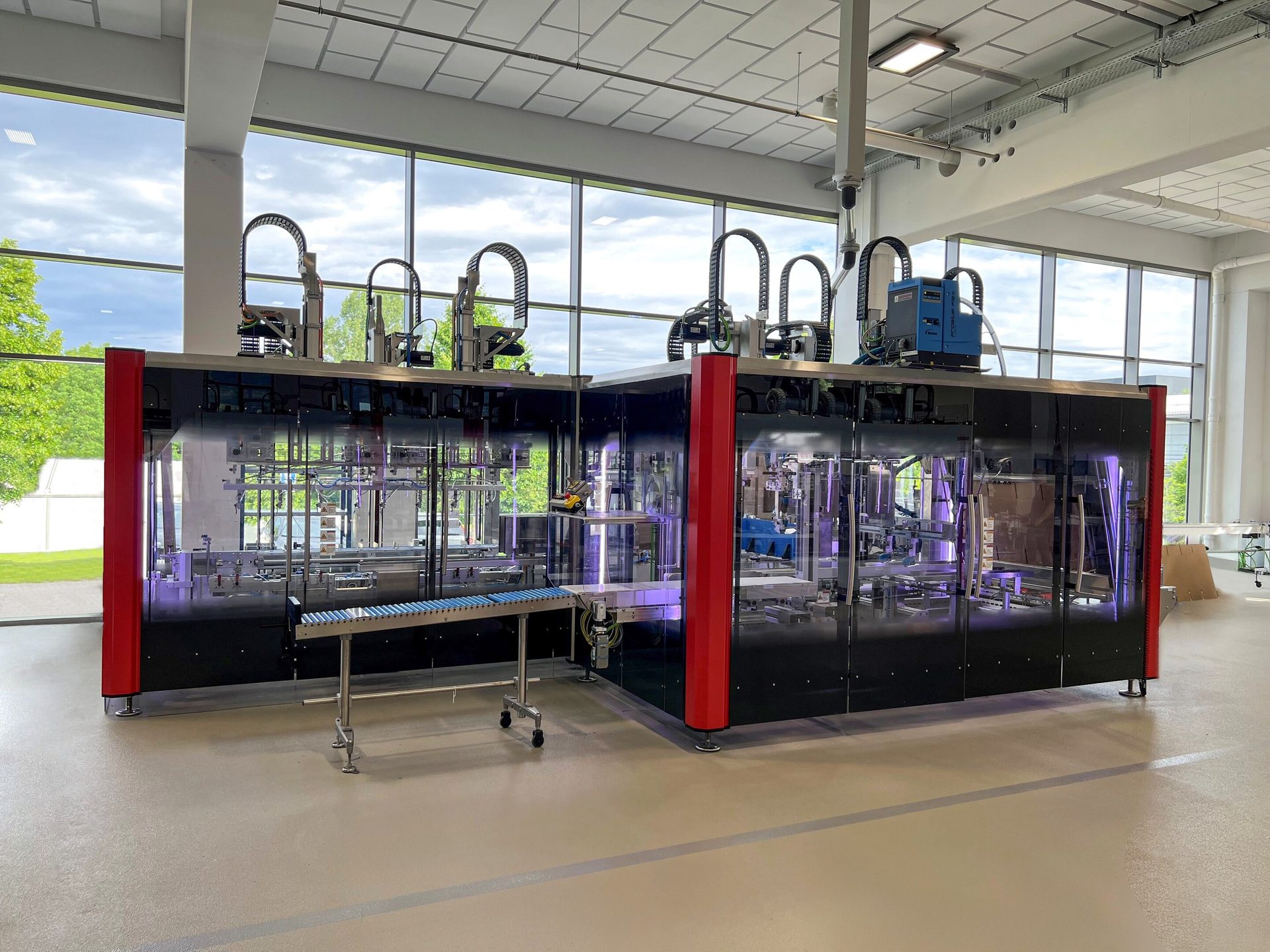 Automated industrial production line in a modern, bright facility with large windows.