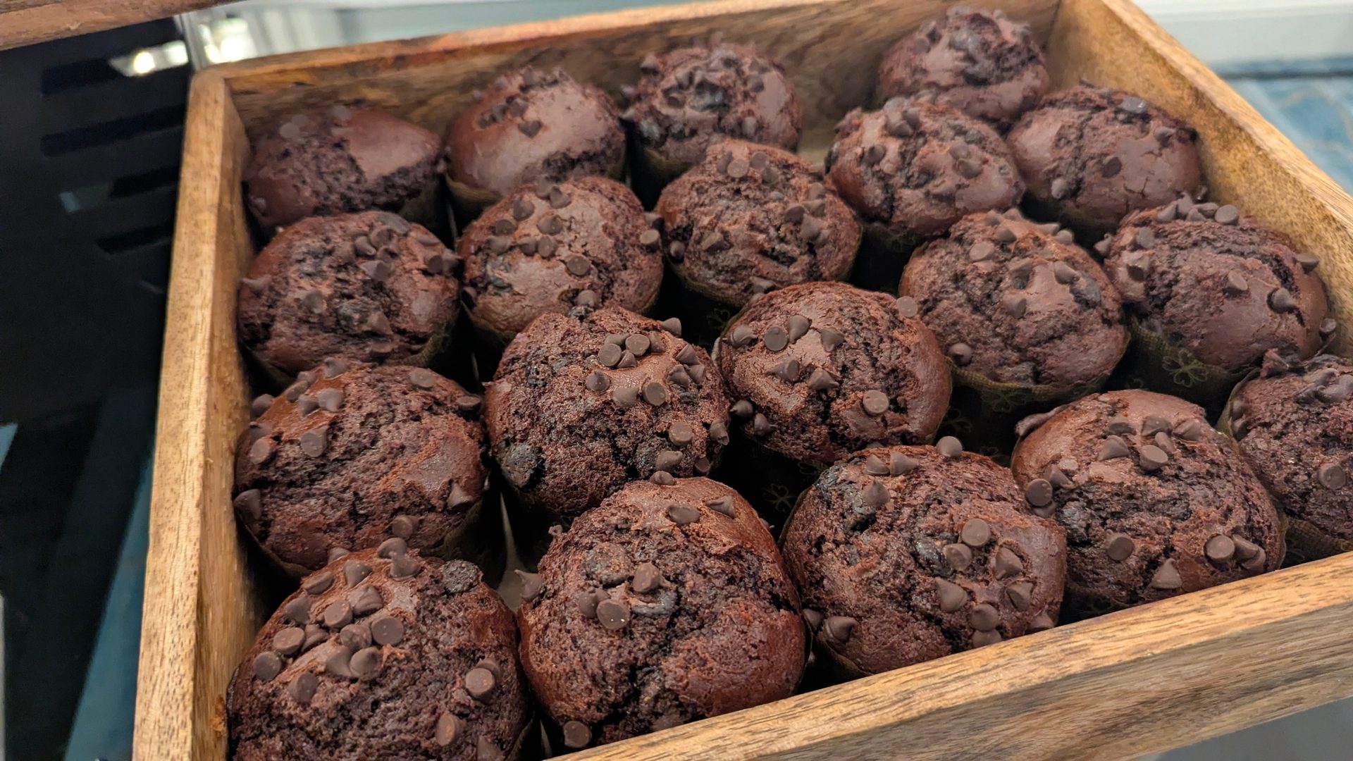Chocolate chip muffins in a wooden tray.