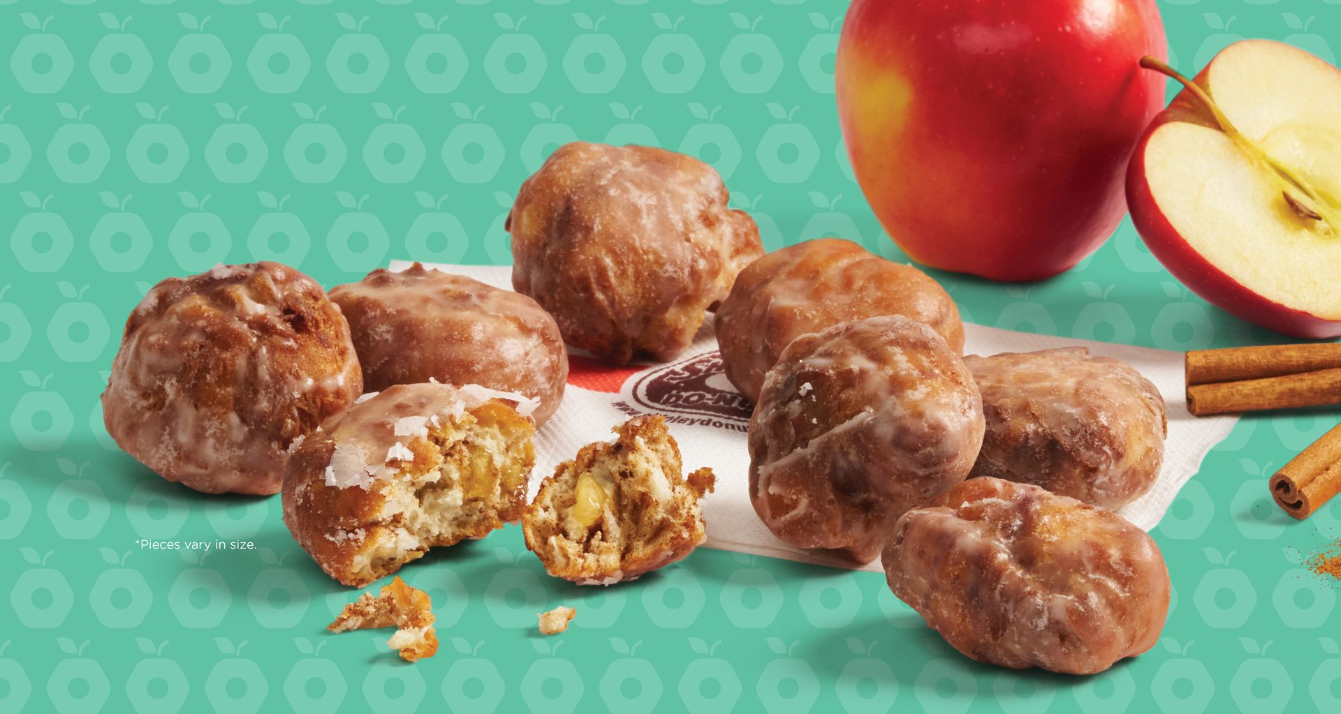 Glazed apple fritters, apples, and cinnamon on a patterned background.