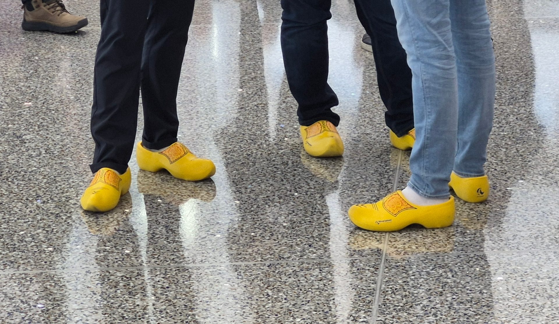 Feet in yellow clogs (klompen) on a reflective floor.