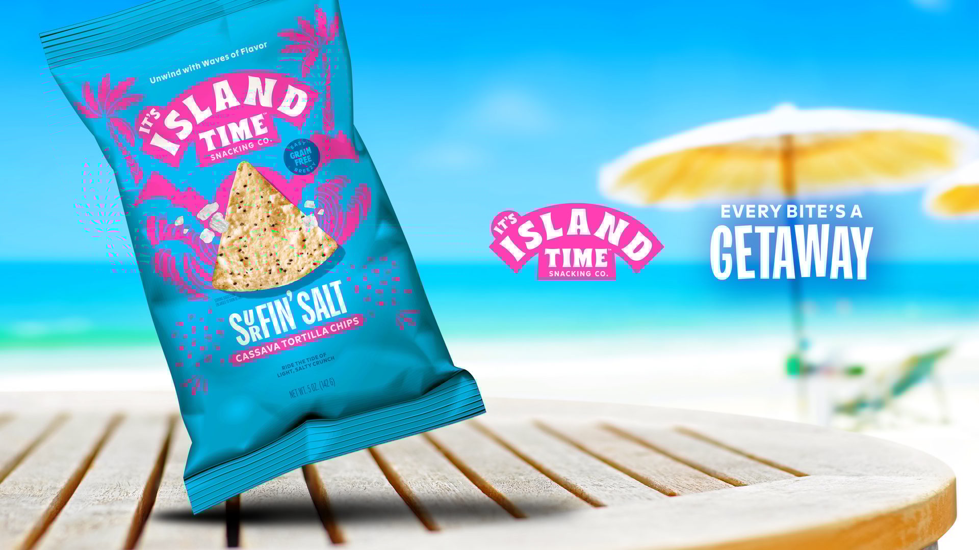 A bag of It's Island Time Surfin' Salt chips on a table, with a beach and "Every Bite's a Getaway".