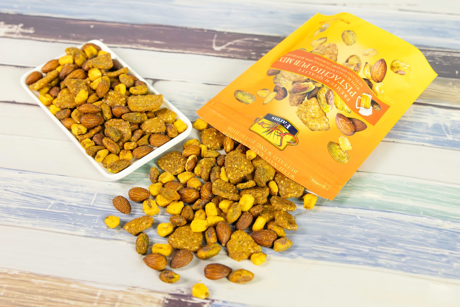 Pistachio Pub Mix bag with nuts spilled and in a bowl on a wooden table.