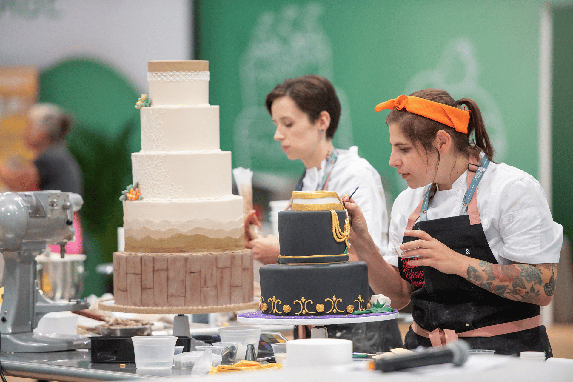 Two women decorating tiered cakes
