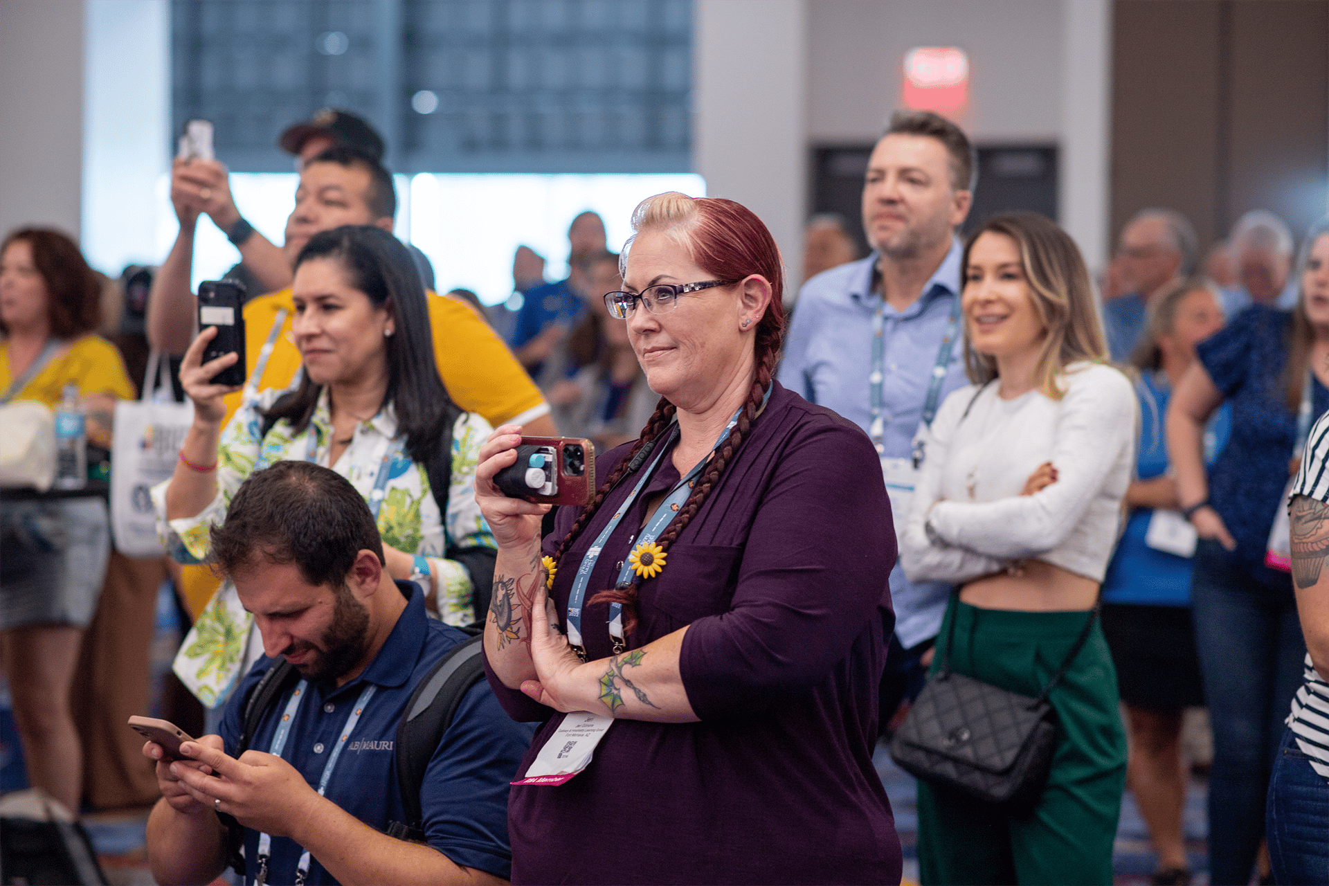 Group of people standing facing one direction, holding up phones