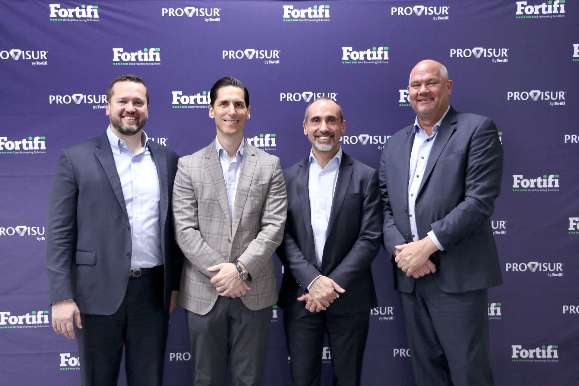 Four smiling men in suits stand against a purple backdrop with Fortifi and Provisur logos.