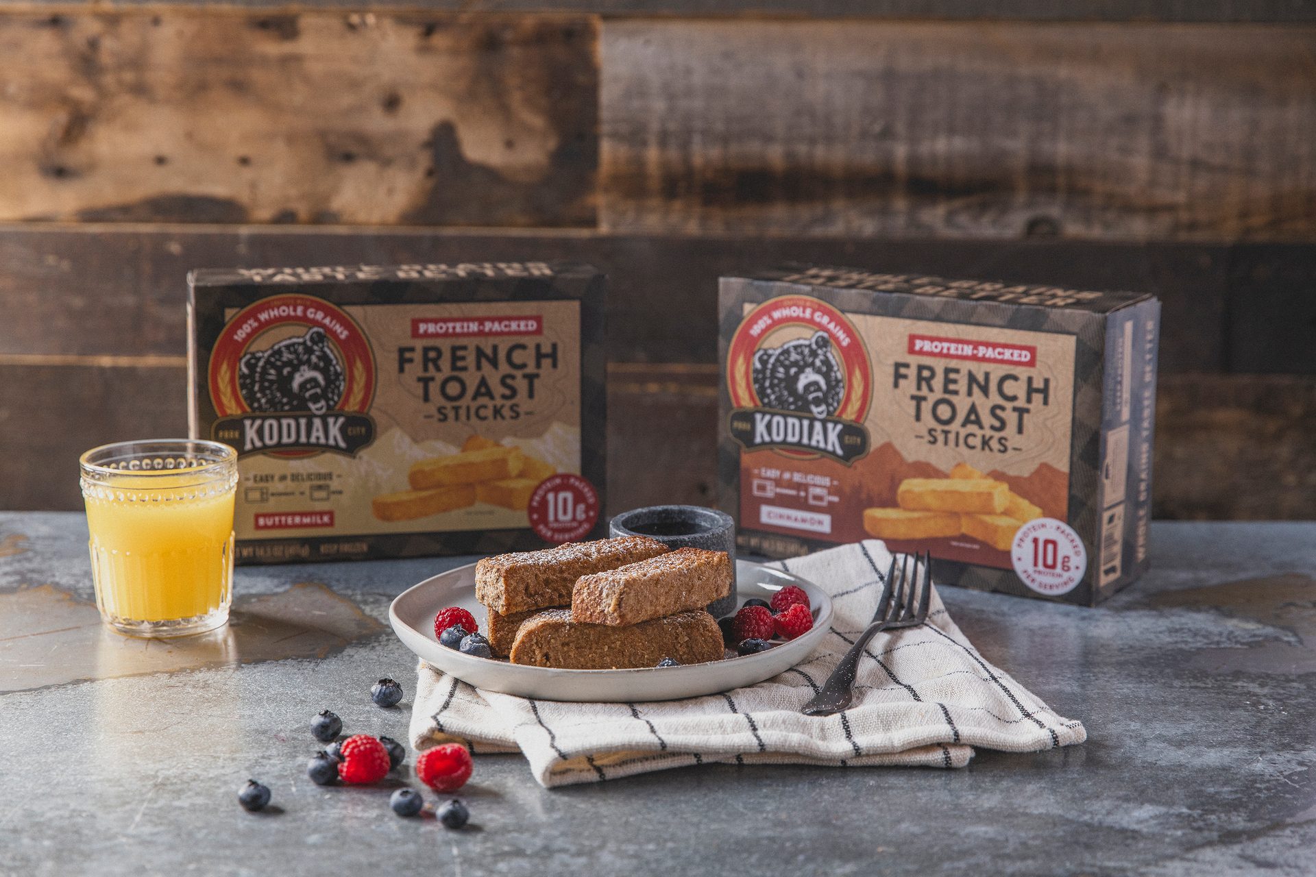 Kodiak French Toast Sticks boxes in the background with orange juice plus French Toast Sticks on a plate