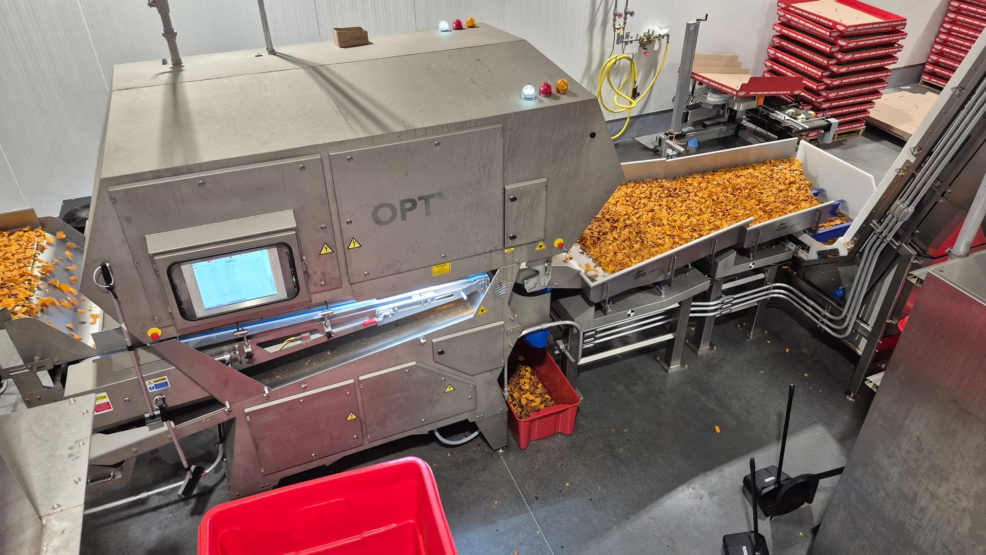 An OPT machine sorting corn chips or similar snack food on a conveyor belt in a processing plant.