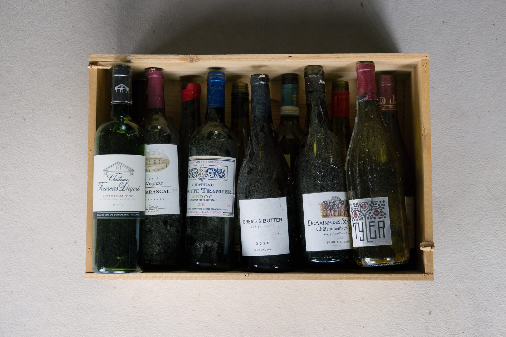 tomme vinflasker i en treboks p&#xE5; et lyst murgulv.