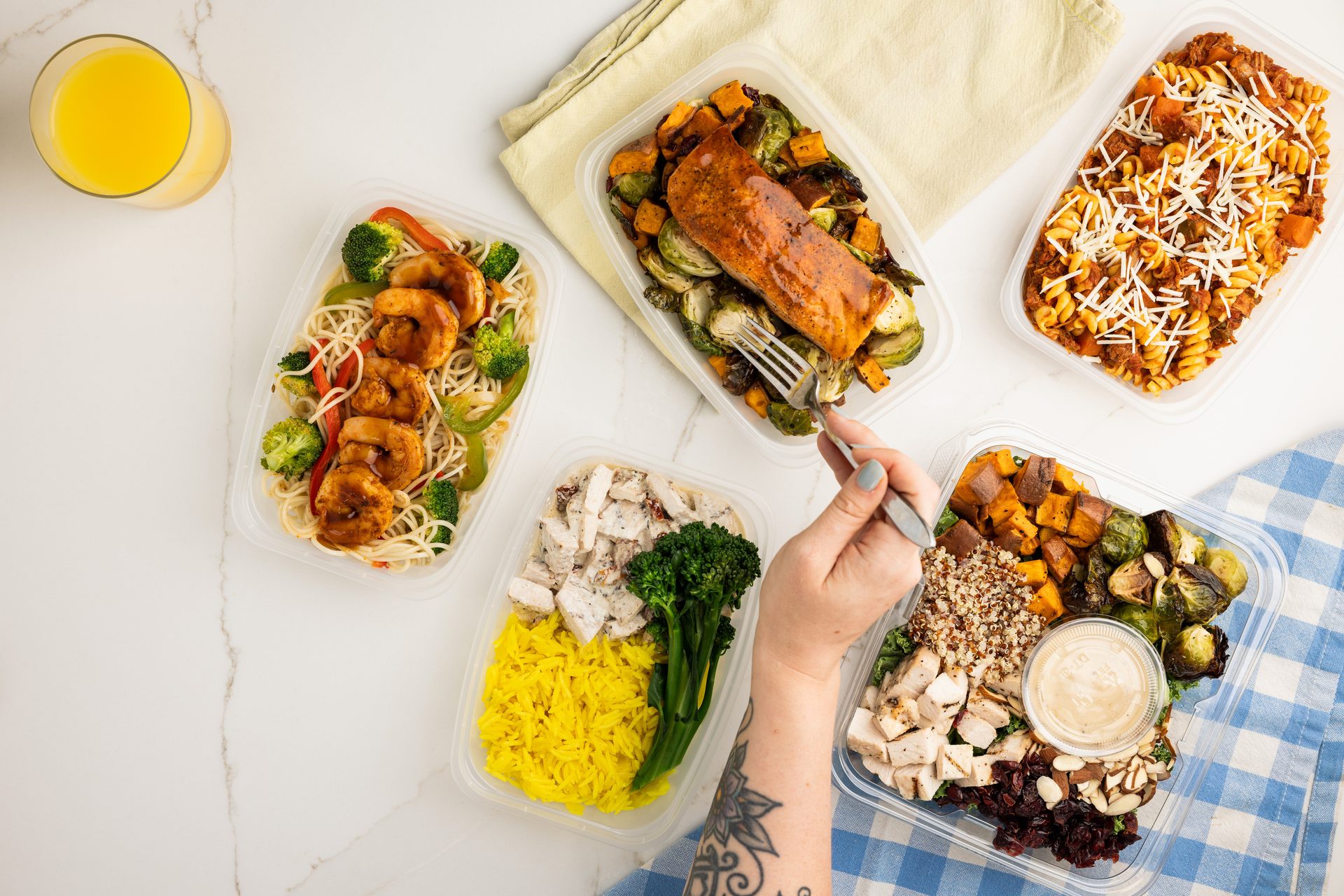 Overhead view of several meal prep containers with healthy dishes like salmon, shrimp, chicken, and pasta.